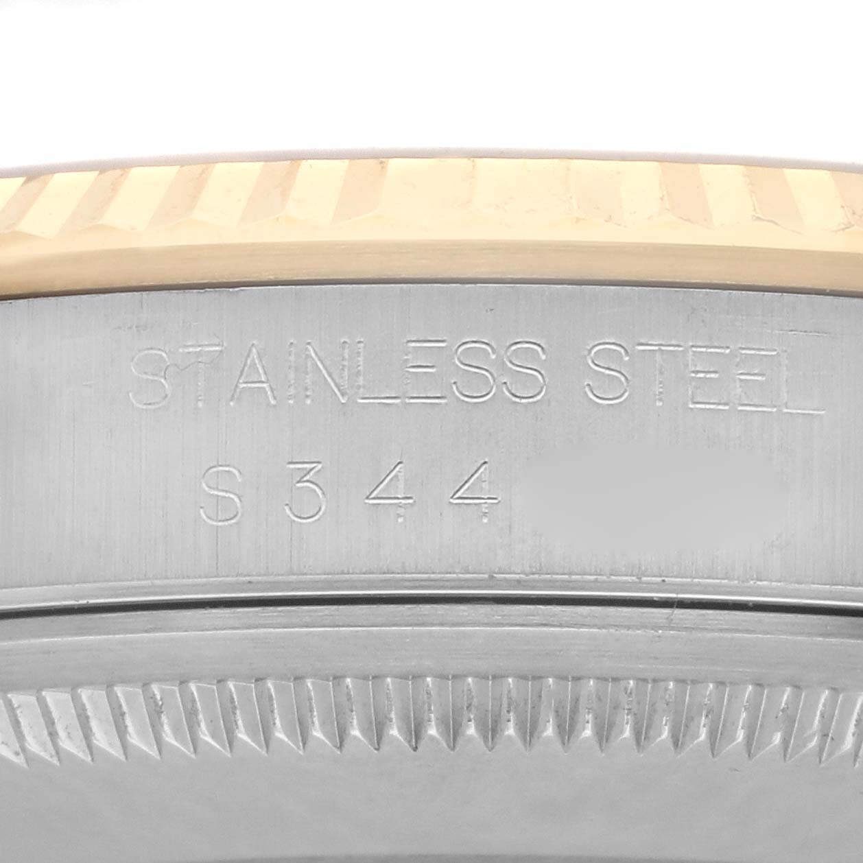 The image shows a close-up of the Rolex Datejust 16233 Men's Steel and Gold (two tone) Champagne Dial 16233 Men's Steel and Gold (two tone) Champagne Dial case edge with "STAINLESS STEEL" and a partial serial number engraved.