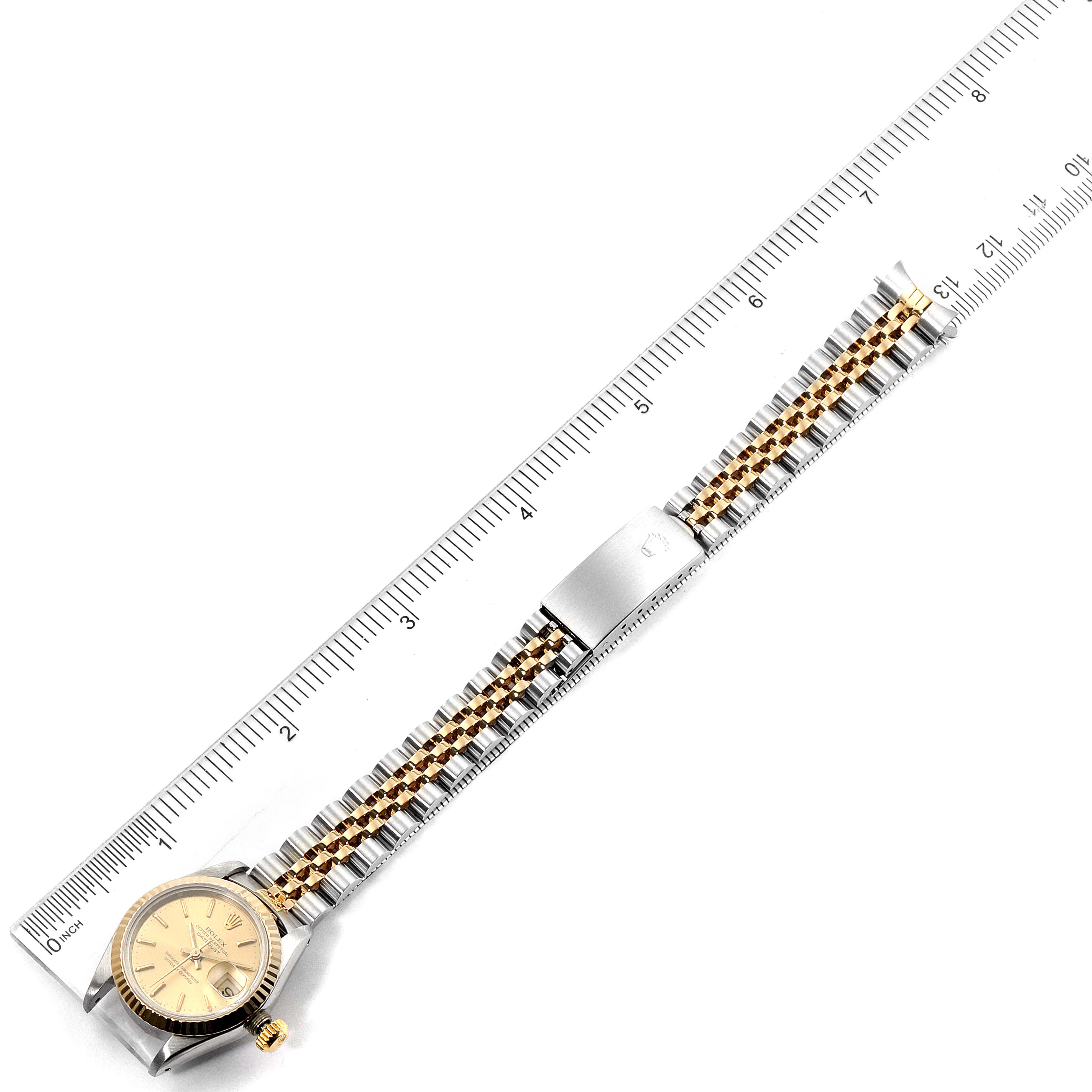 The Rolex Datejust 69173 Women
s Steel and Gold (two tone) Champagne Dial 69173 Women
s Steel and Gold (two tone) Champagne Dial watch is displayed flat alongside a ruler, showing its face, bracelet, and clasp.