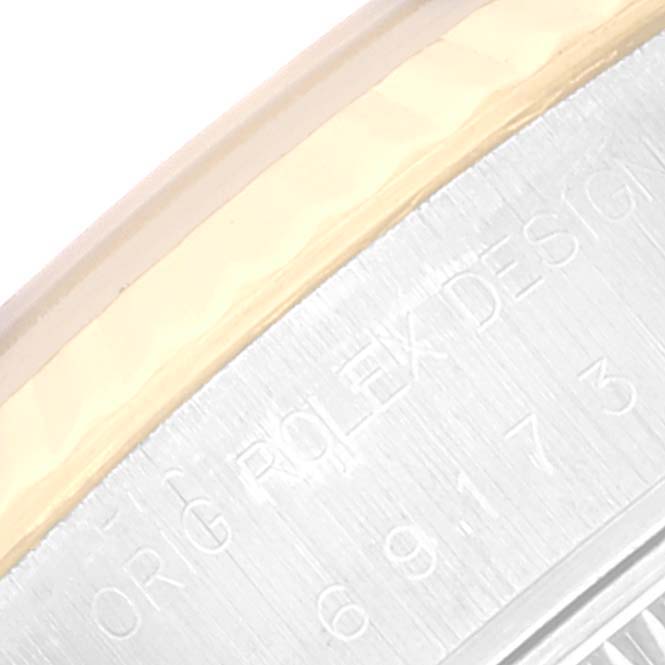 The image shows a close-up angle of the edge of the bezel and part of the case back of the Rolex Datejust 69173 Women's Steel and Gold (two tone) Beige Dial 69173 Women's Steel and Gold (two tone) Beige Dial watch displaying engravings.