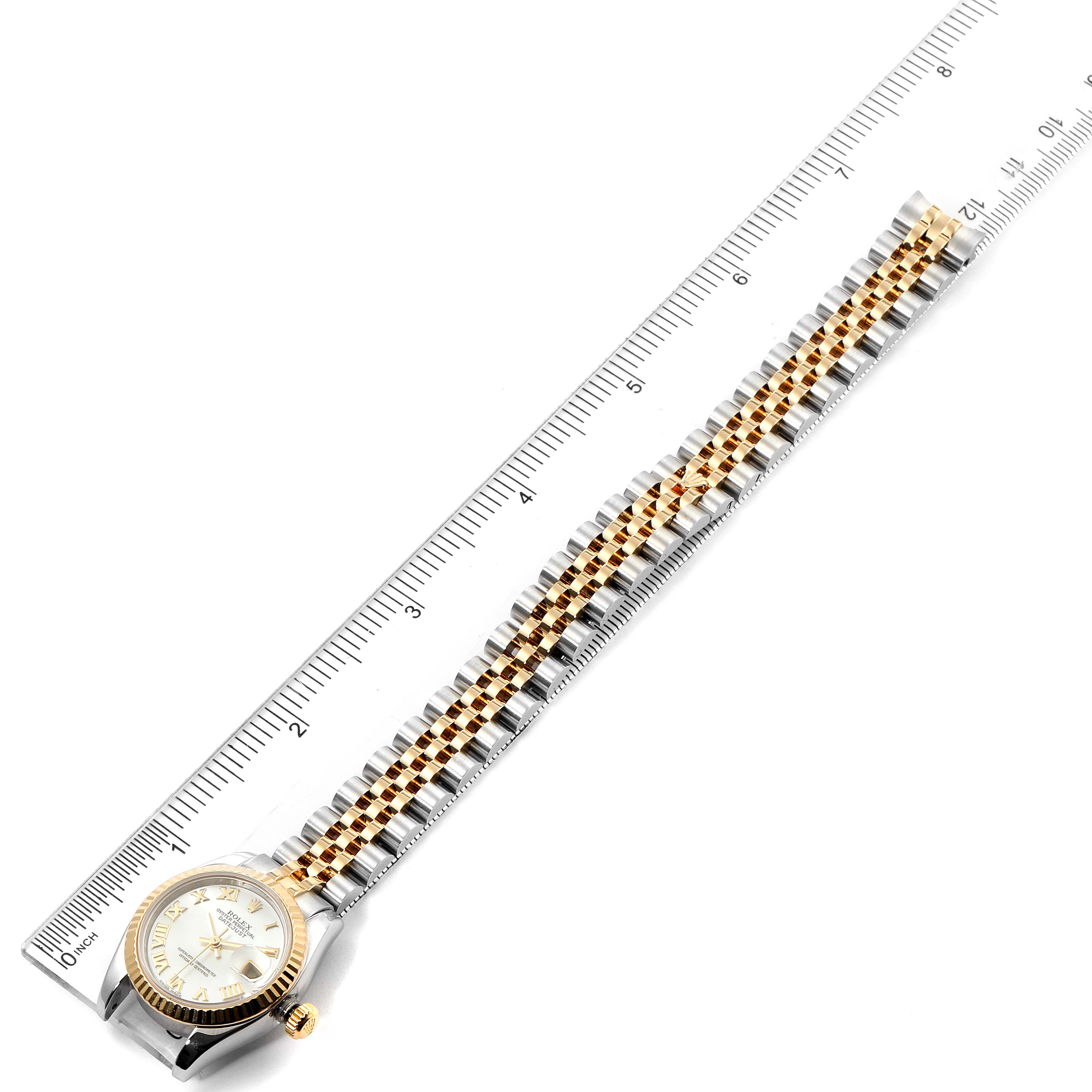 This image shows a Rolex Datejust 179173 Women
s Steel and Gold (two tone) Mother of Pearl Dial 179173 Women
s Steel and Gold (two tone) Mother of Pearl Dial watch with a two-tone bracelet placed next to a ruler for measurement.