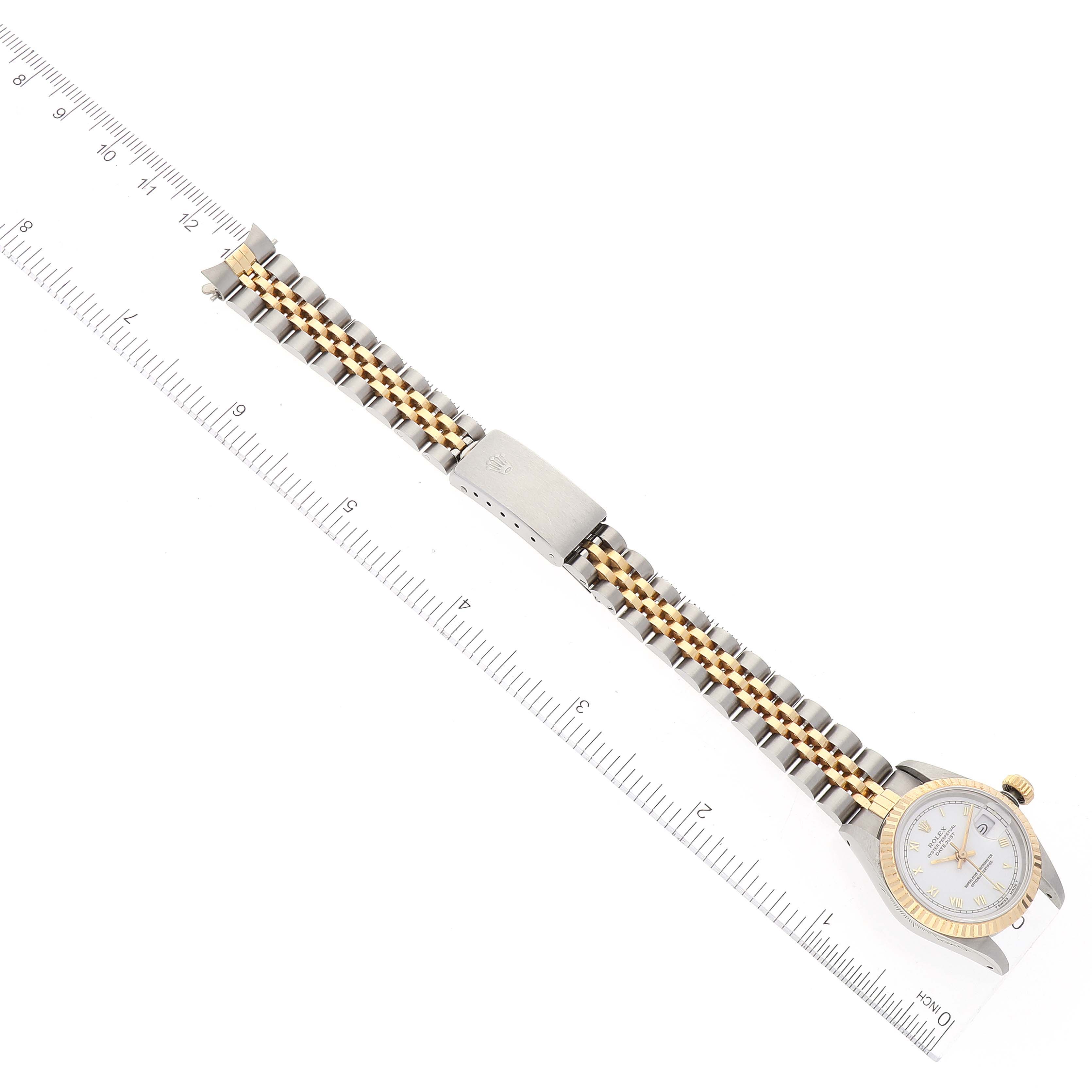The image shows an overhead view of a Rolex Datejust 69173 Women's Steel and Gold (two tone) White Dial 69173 Women's Steel and Gold (two tone) White Dial watch, with its bracelet and clasp extended along a ruler for scale.