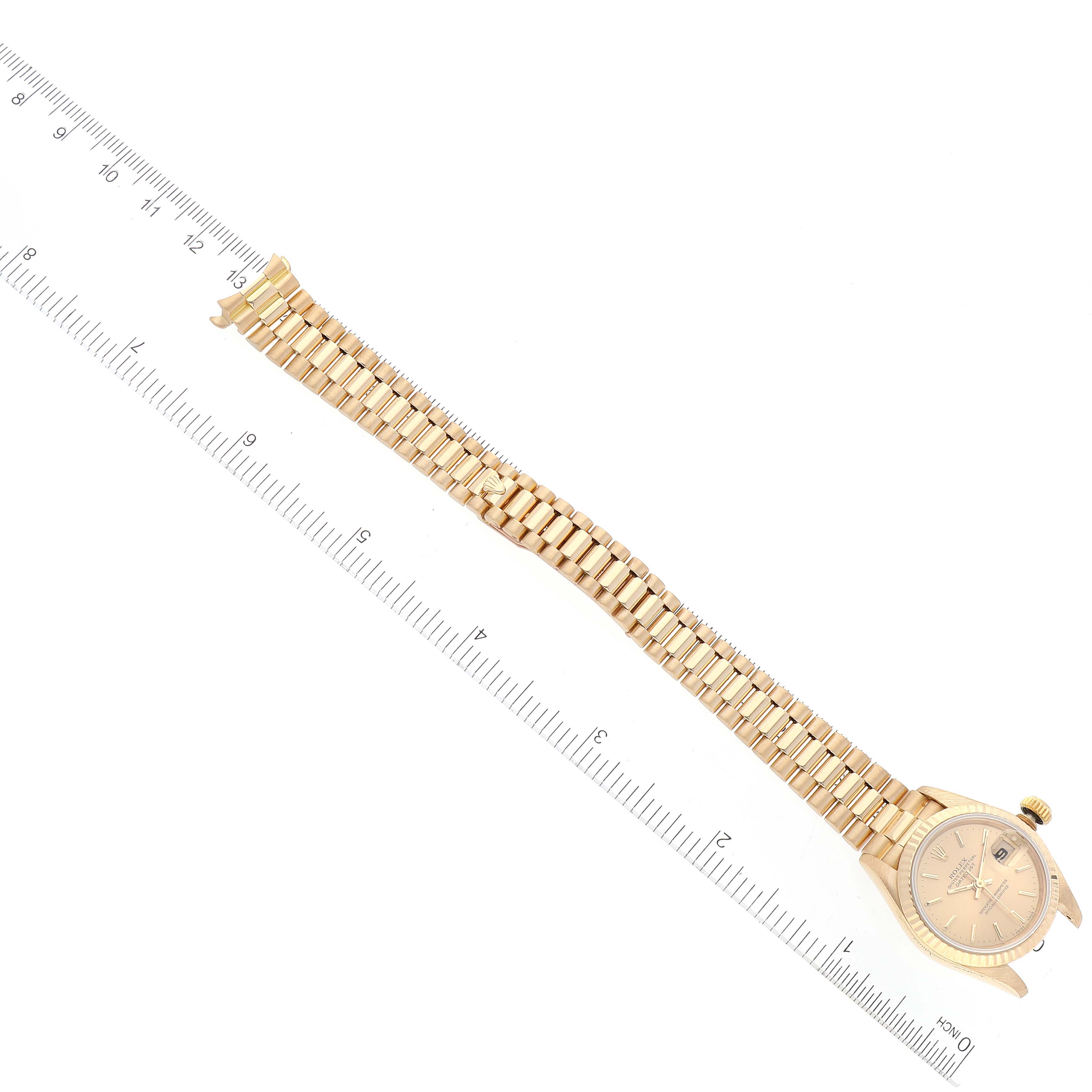 The image shows a Rolex President 69178 Women's Yellow Gold Champagne Dial 69178 Women's Yellow Gold Champagne Dial model watch laid flat with its band extended next to a ruler for measurement.