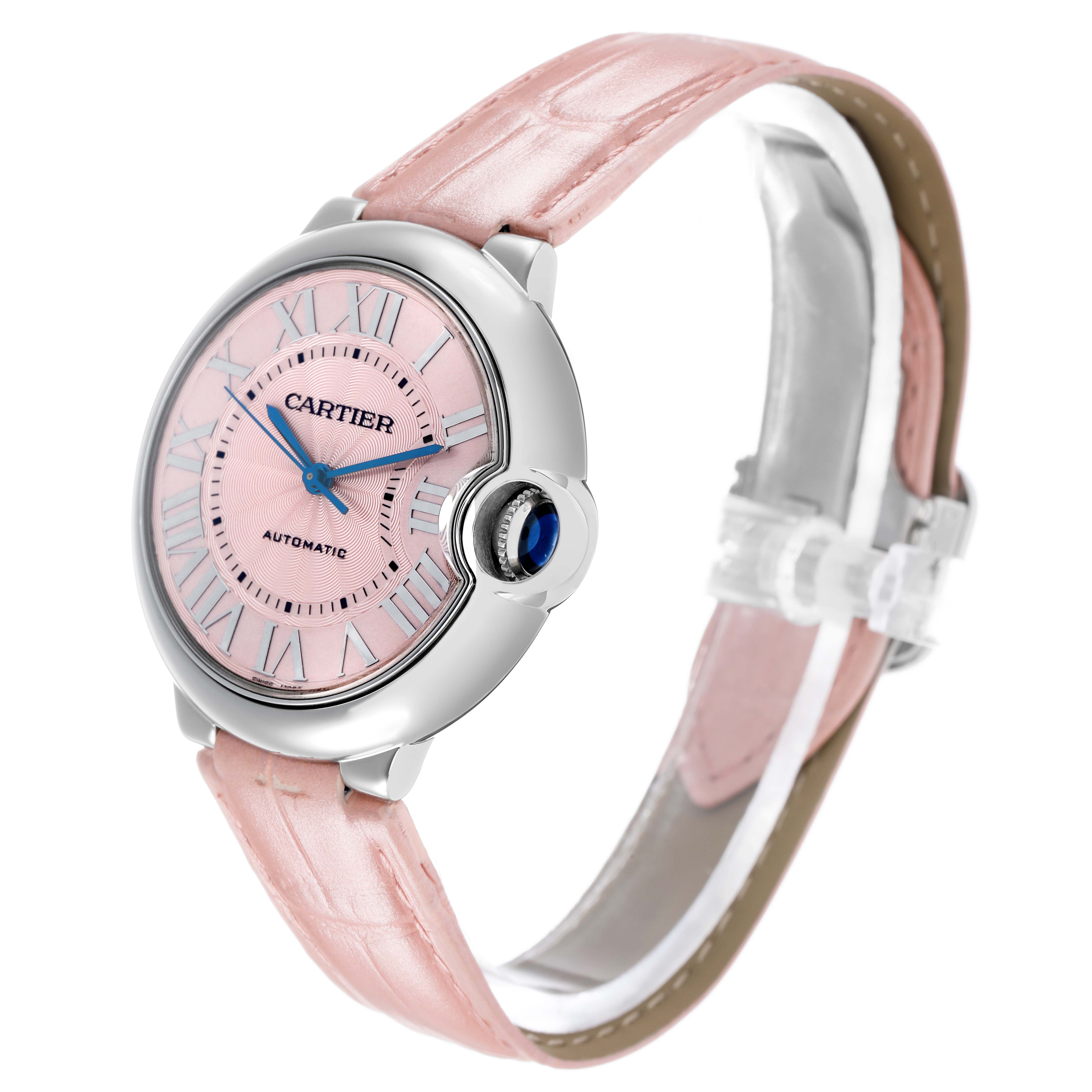 The Cartier Ballon Bleu WSBB0007 Women's Stainless Steel Pink Dial watch is shown at a front-facing angle, highlighting its pink dial, blue hands, crown with a blue cabochon, and pink strap.