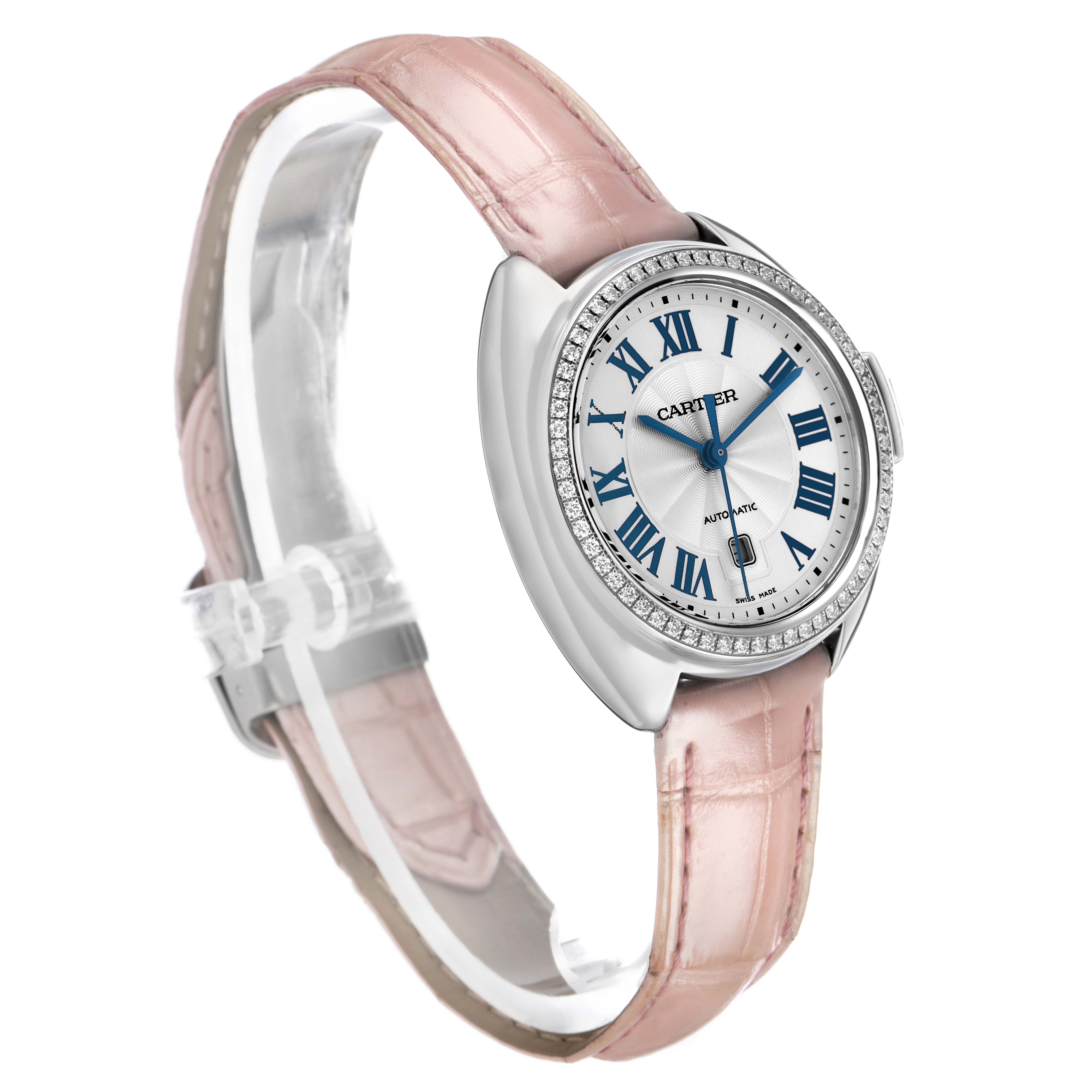 The Cartier Clé watch is shown at a three-quarter angle, highlighting its pink leather strap, diamond bezel, and Roman numeral dial.