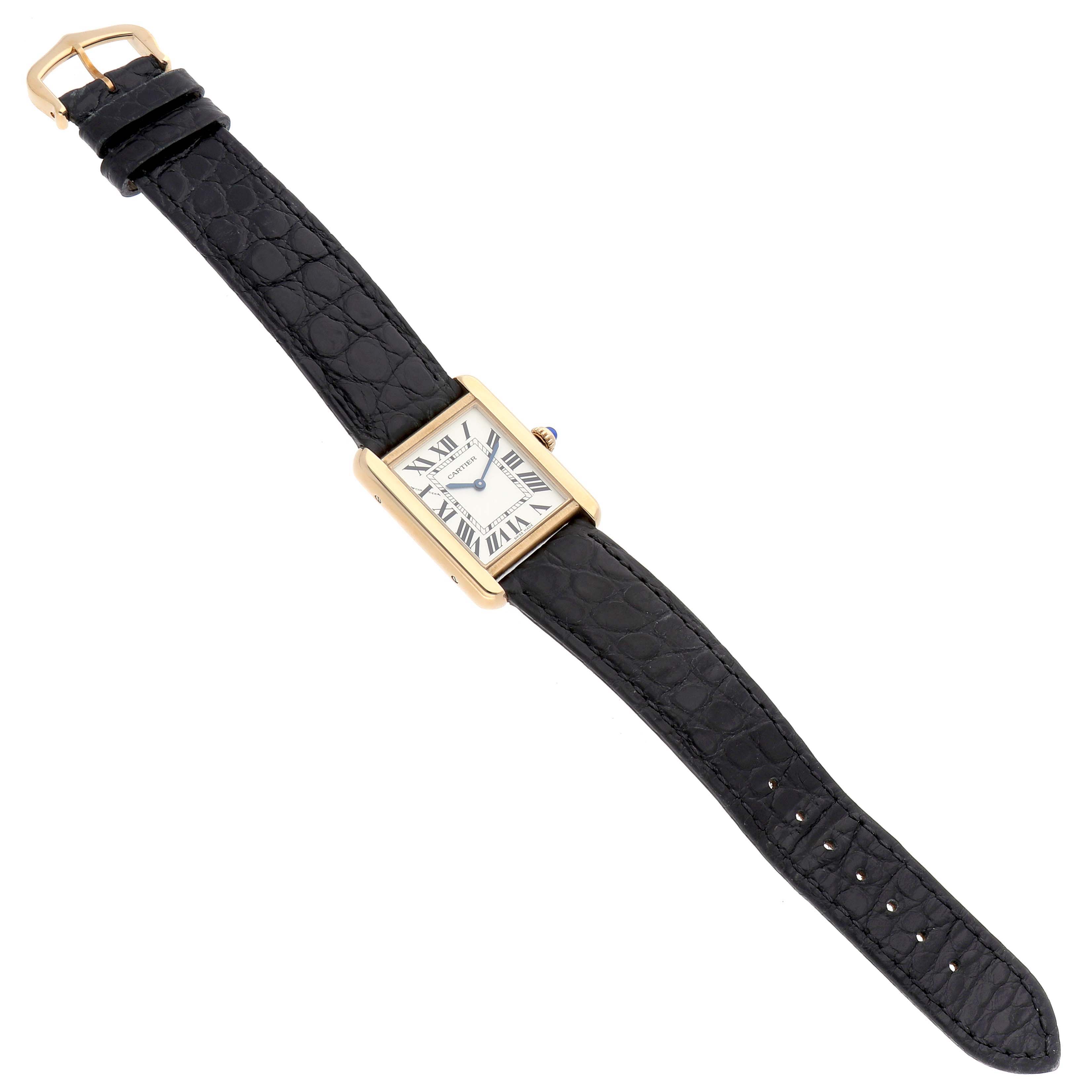 The Cartier Tank Solo W5200002 Women's Steel and Gold (two tone) Silver Dial watch is shown from an overhead angle, highlighting its rectangular face, gold casing, and black leather strap.