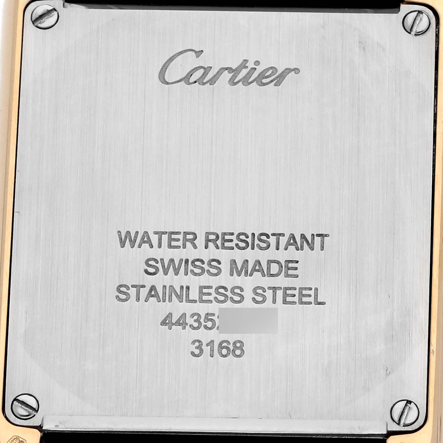 The image shows the back case of a Cartier Tank Solo W5200002 Women's Steel and Gold (two tone) Silver Dial watch, featuring engraved details and screws at the corners.