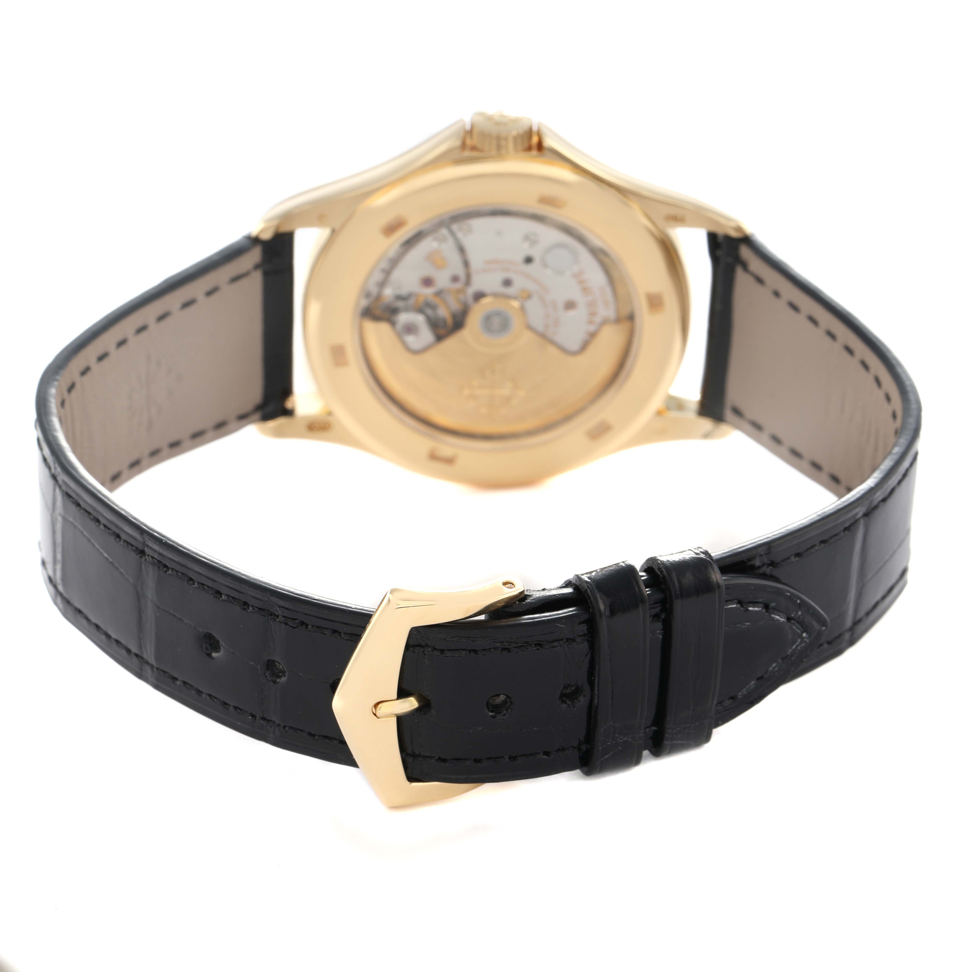 The image shows the back view of a Patek Philippe Calatrava 5107J Men's Yellow Gold Silver Dial with its open case back and black leather strap with a gold buckle.