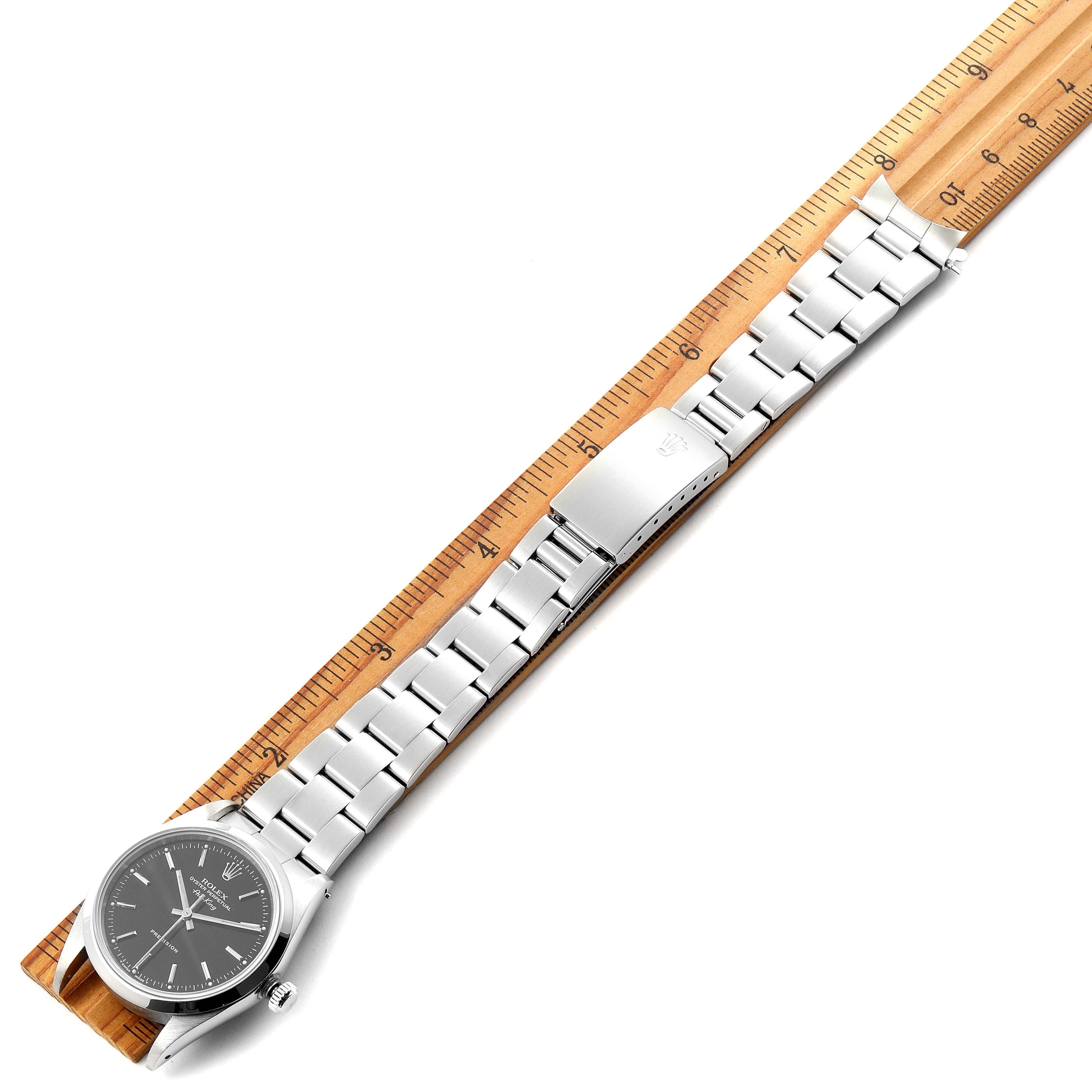 The image shows a top view of a Rolex Air-King 14000 Men's Stainless Steel Black Dial 14000 Men's Stainless Steel Black Dial watch and its metal bracelet, placed alongside a wooden ruler for scale.