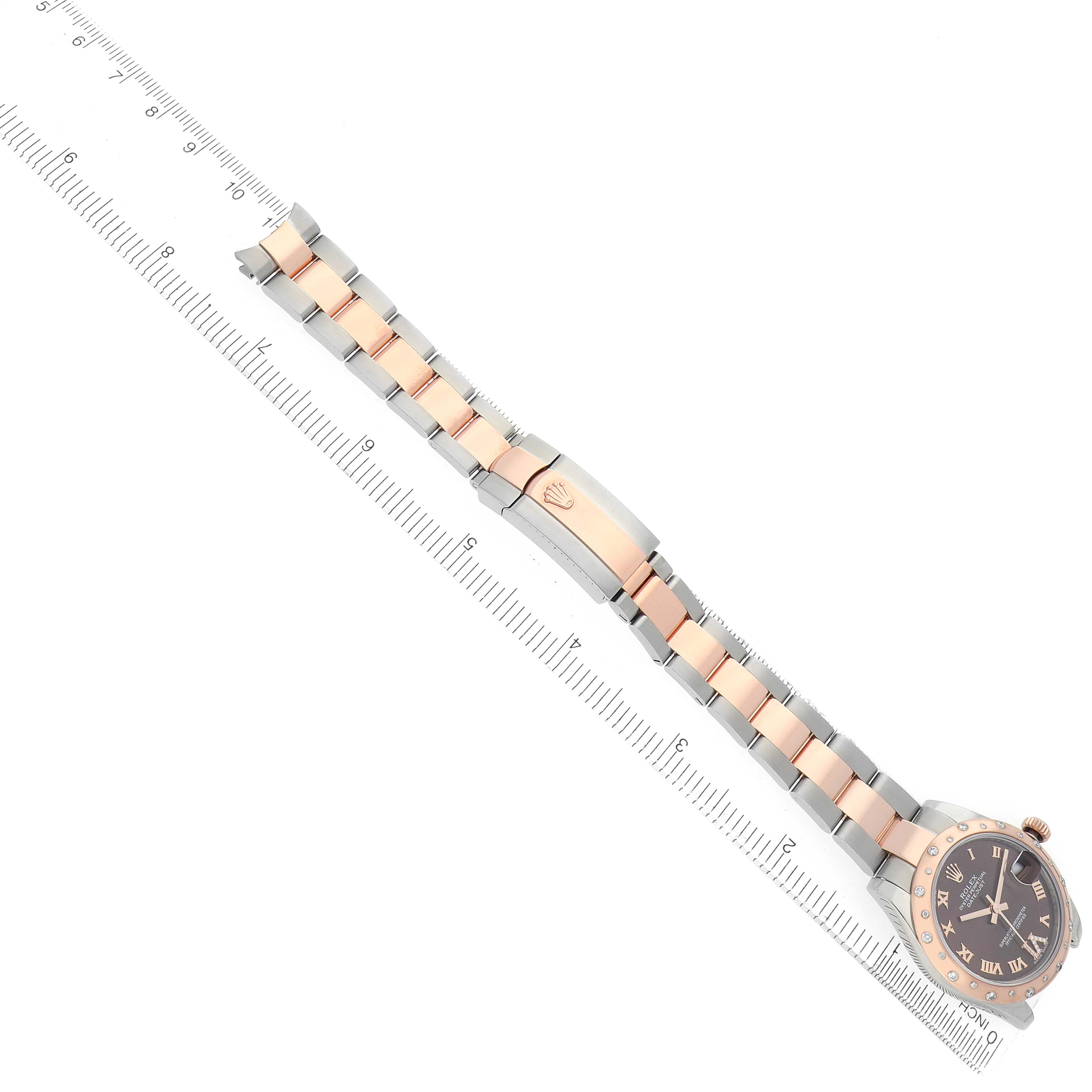 The Rolex Mid-Size 178341 Women's Steel and Gold (two tone) Brown Dial watch is displayed diagonally, highlighting the bracelet, clasp, bezel, and face, with a ruler for scale.