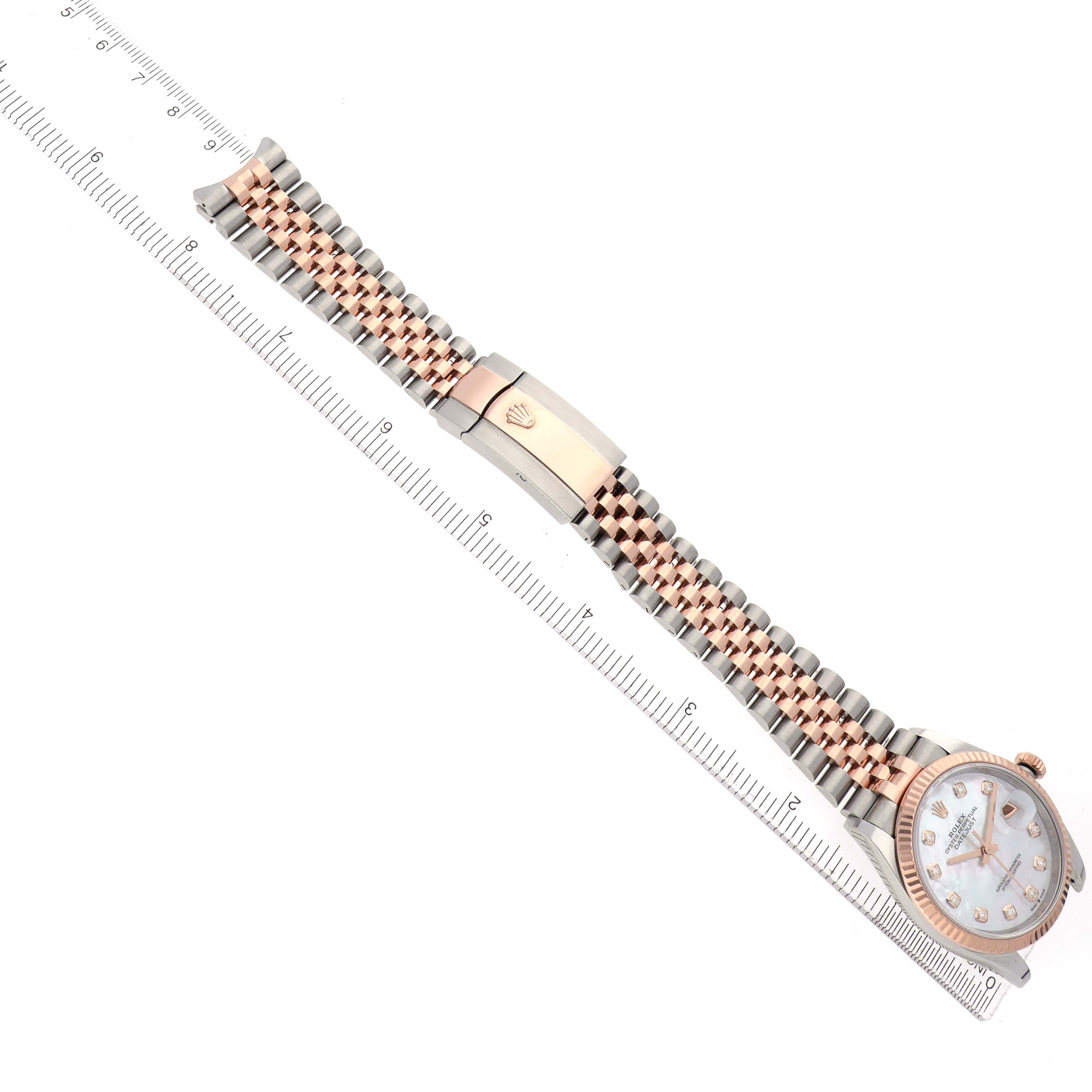 The Rolex Datejust 126231 Men's Steel and Gold (two tone) Mother of Pearl Dial watch is shown top-down with a focus on the bracelet, clasp, and face next to a ruler.