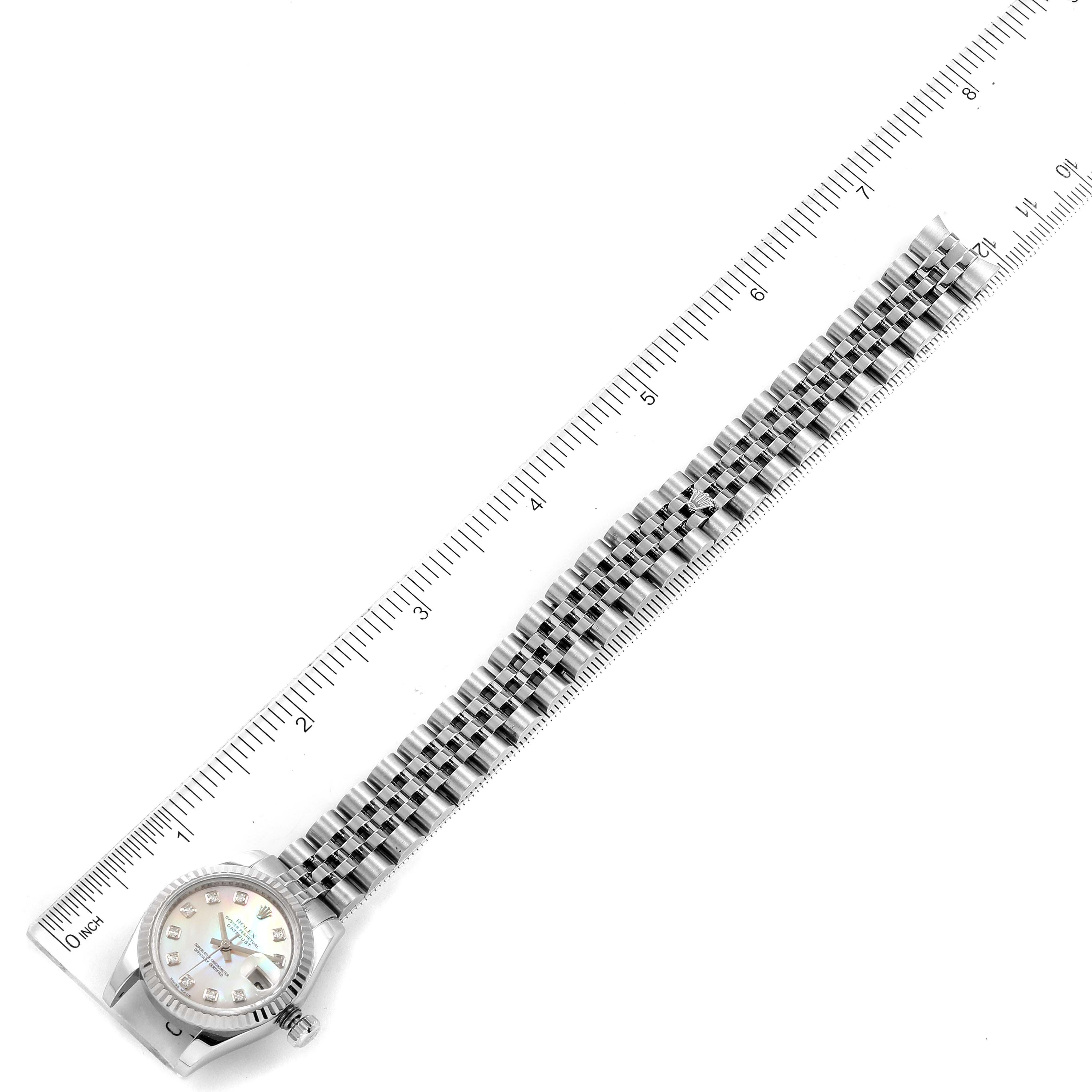 The Rolex Datejust 179174 Women
s Stainless Steel Mother of Pearl Dial 179174 Women
s Stainless Steel Mother of Pearl Dial watch is shown from a top-down angle, displaying its face, case, and entire bracelet, aligned with a ruler.