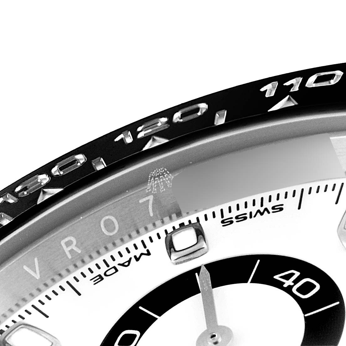 This image shows a close-up of the bezel and part of the dial of a Rolex Daytona 116500 Men's Stainless Steel White Dial 116500 Men's Stainless Steel White Dial watch.