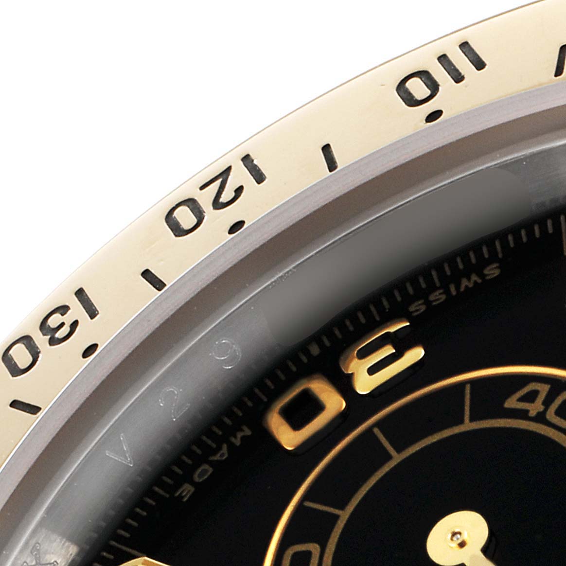 The image shows a close-up of the bezel and part of the dial of a Rolex Daytona 116523 Men
s Steel and Gold (two tone) Black Dial 116523 Men
s Steel and Gold (two tone) Black Dial watch.