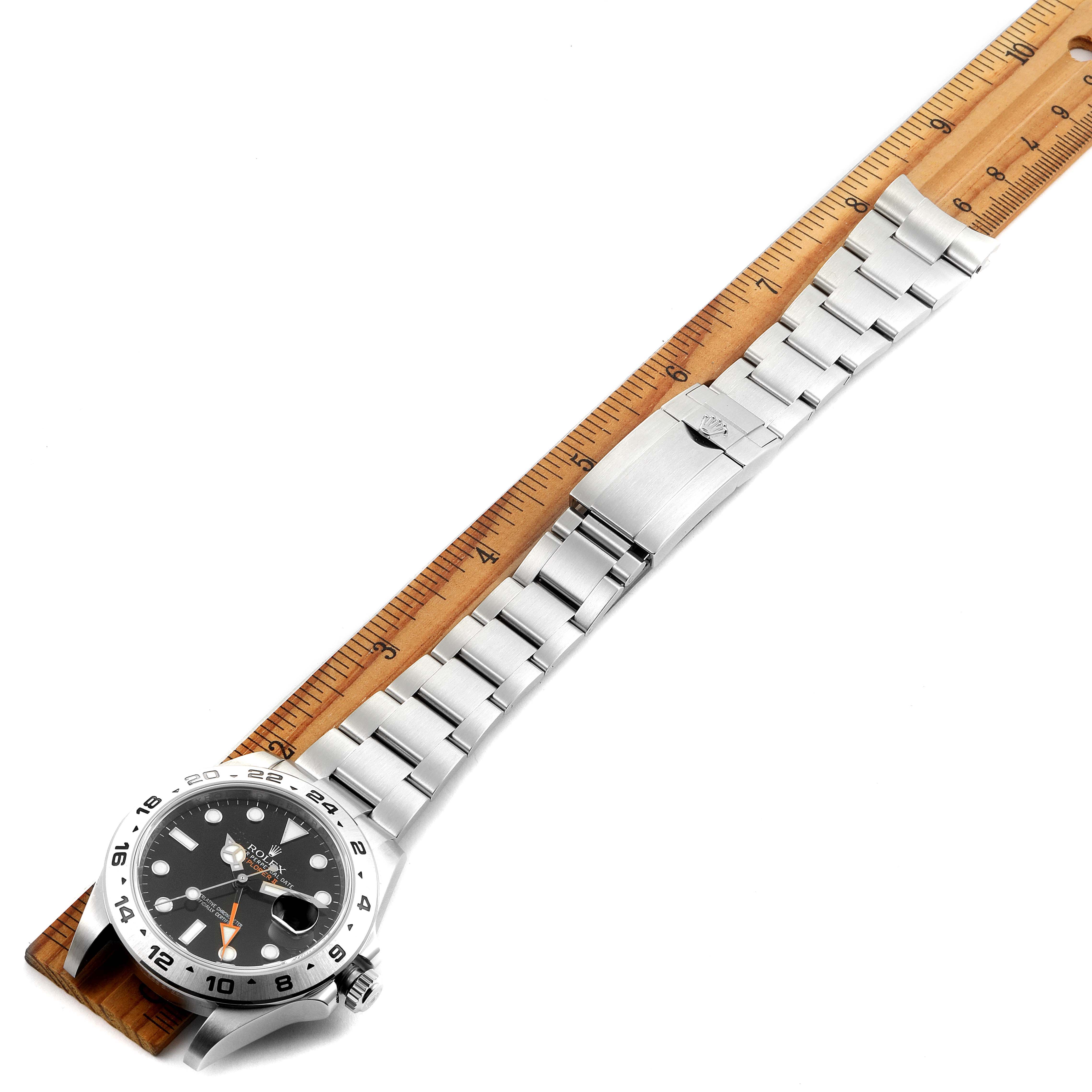 The Rolex Explorer 216570 Men
s Stainless Steel Black Dial 216570 Men
s Stainless Steel Black Dial watch is shown at an angle, displaying the face, bracelet, and clasp next to a ruler for size reference.