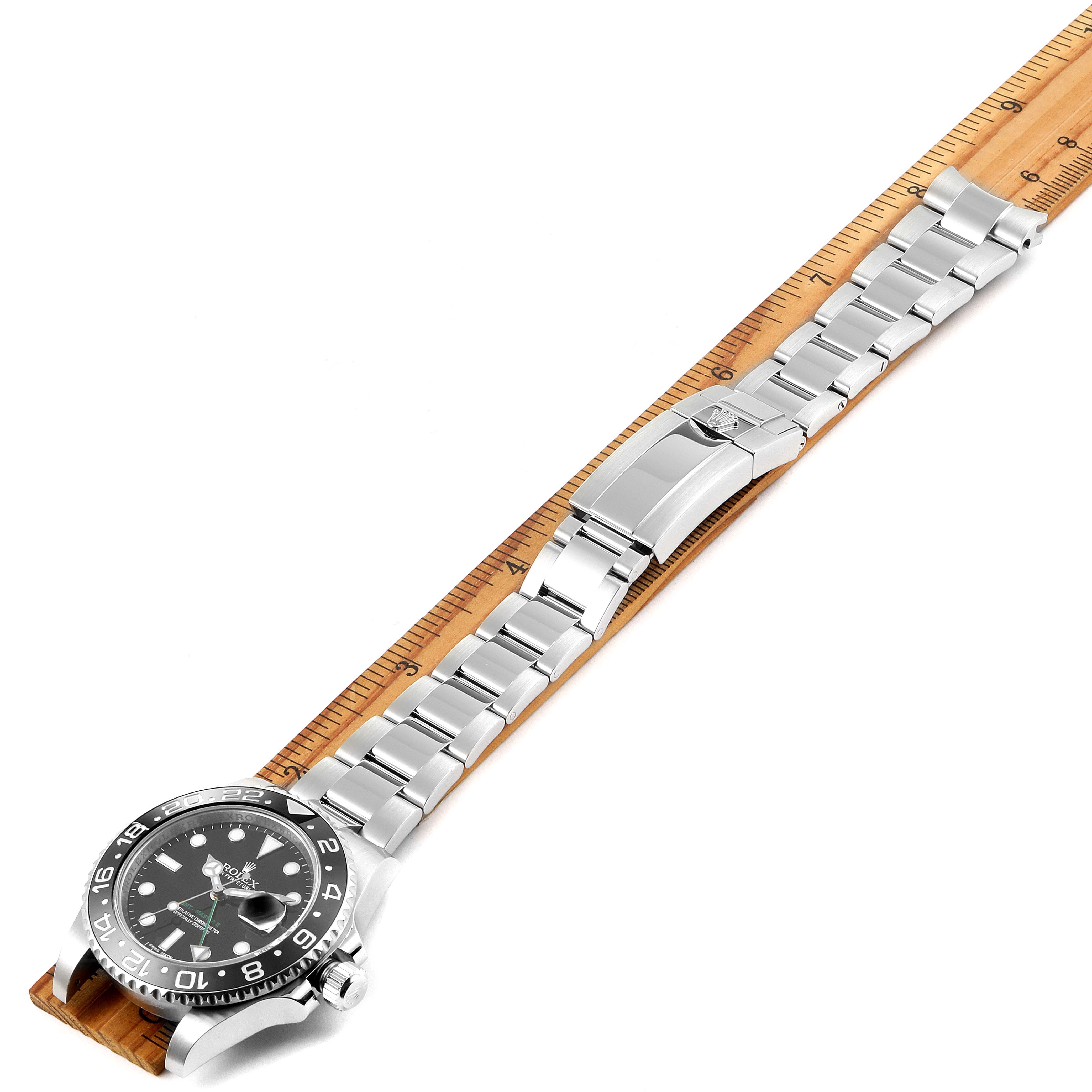The image shows the Rolex GMT-Master 116710 Men
s Stainless Steel Black Dial 116710 Men
s Stainless Steel Black Dial watch lying flat with its dial, case, and full bracelet visible, placed against a ruler for scale.