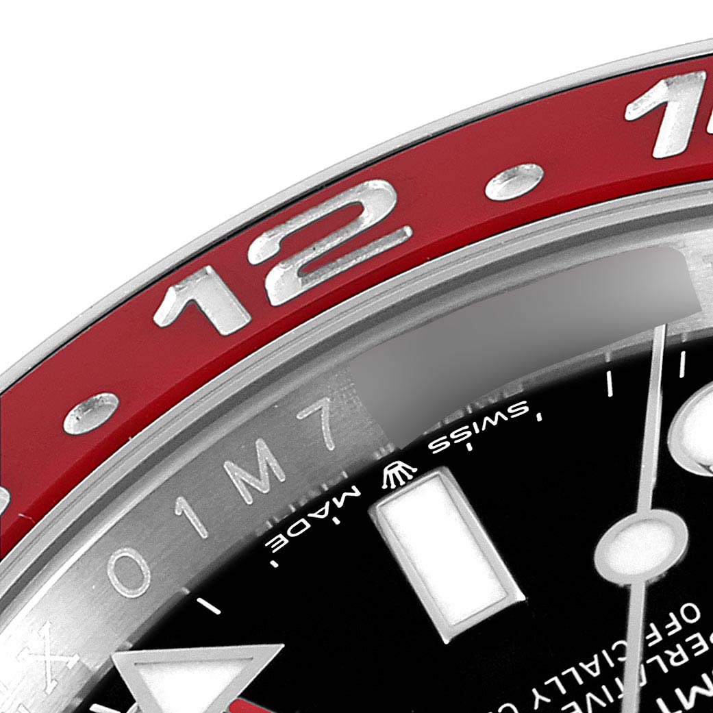 This close-up image shows part of the bezel and dial of a Rolex GMT-Master 126710 Men
s Stainless Steel Black Dial 126710 Men
s Stainless Steel Black Dial watch, featuring the "12" marker and some text.