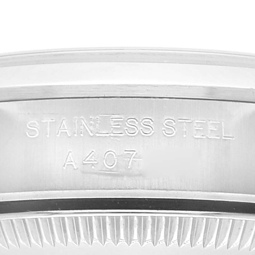 The image shows a close-up of the side of a stainless steel bezel of a Rolex Oyster Perpetual 76080 Women
s Stainless Steel Pink Dial 76080 Women
s Stainless Steel Pink Dial watch with engraved text.