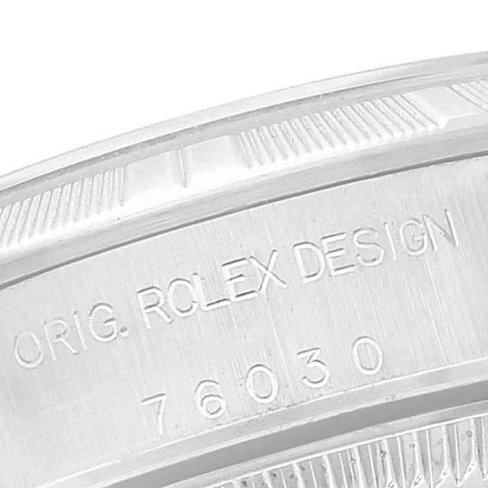 The image shows an angled close-up of the case back of a Rolex Oyster Perpetual 76030 Women
s Stainless Steel Pink Dial 76030 Women
s Stainless Steel Pink Dial watch, highlighting the engraved model number and "ORIG. ROLEX DESIGN."