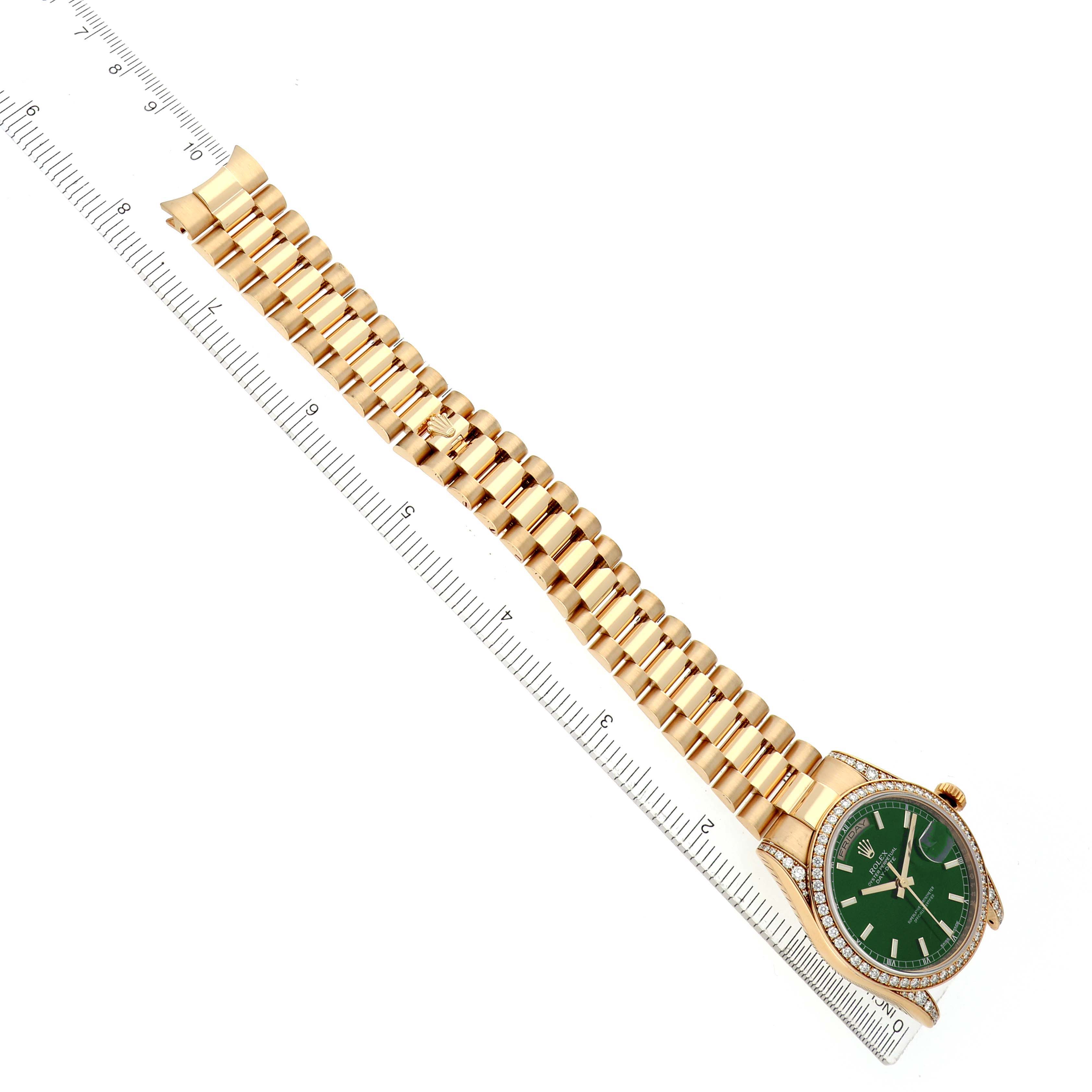 The Rolex President 118388 Men's Yellow Gold Green Dial model watch is shown from a top view, displaying the face, bezel, and full bracelet aligned beside a ruler.