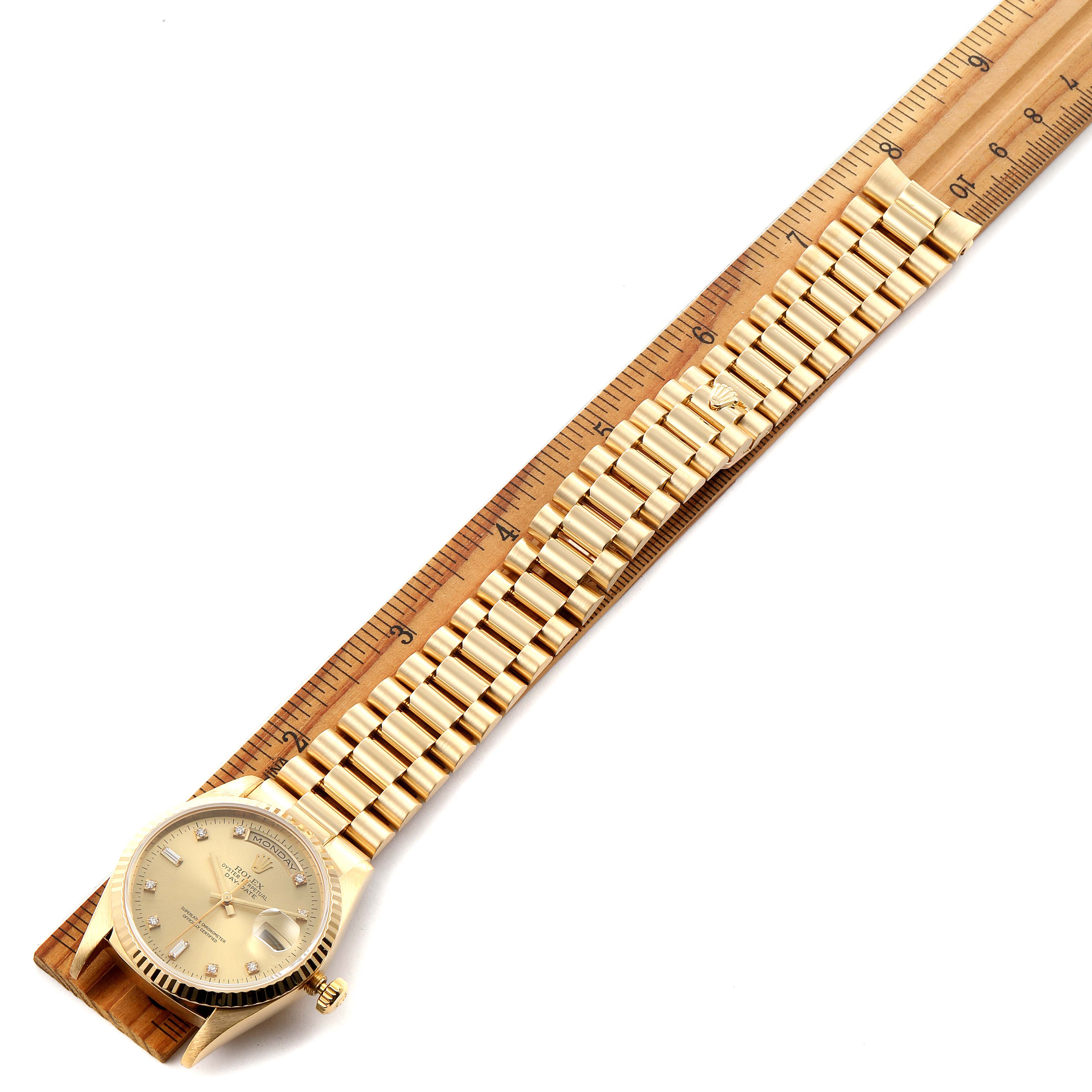 The image shows a Rolex President 18238 Men
s Yellow Gold Champagne Dial 18238 Men
s Yellow Gold Champagne Dial watch laid flat on a ruler, showcasing the watch face and bracelet.