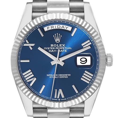 The image shows a front view of a Rolex President model, featuring its blue dial, date display, and fluted bezel.