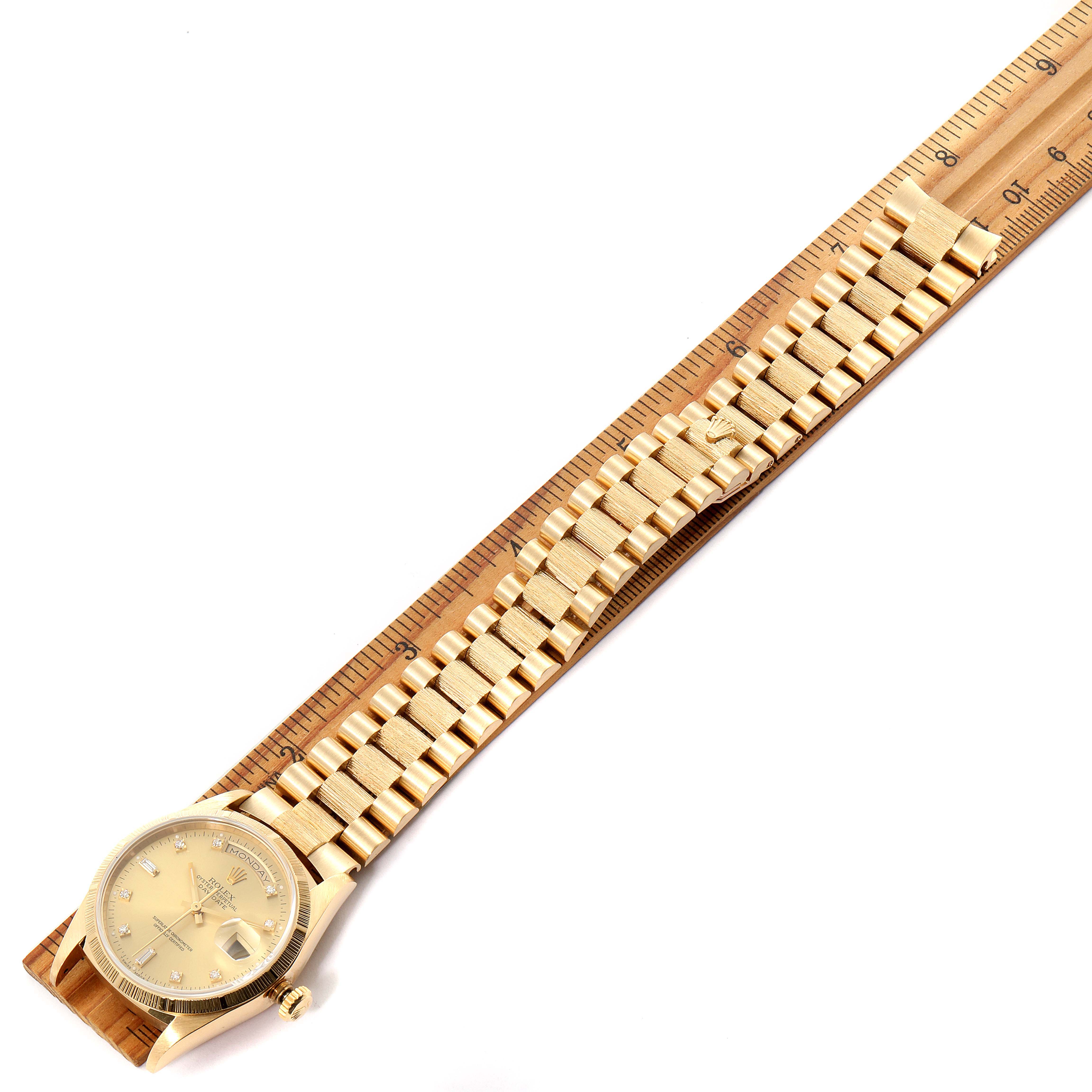 The Rolex President 18248 Men's Yellow Gold Champagne Dial 18248 Men's Yellow Gold Champagne Dial model watch is shown from an angled top view, highlighting its case, bezel, dial, and bracelet alongside a ruler.