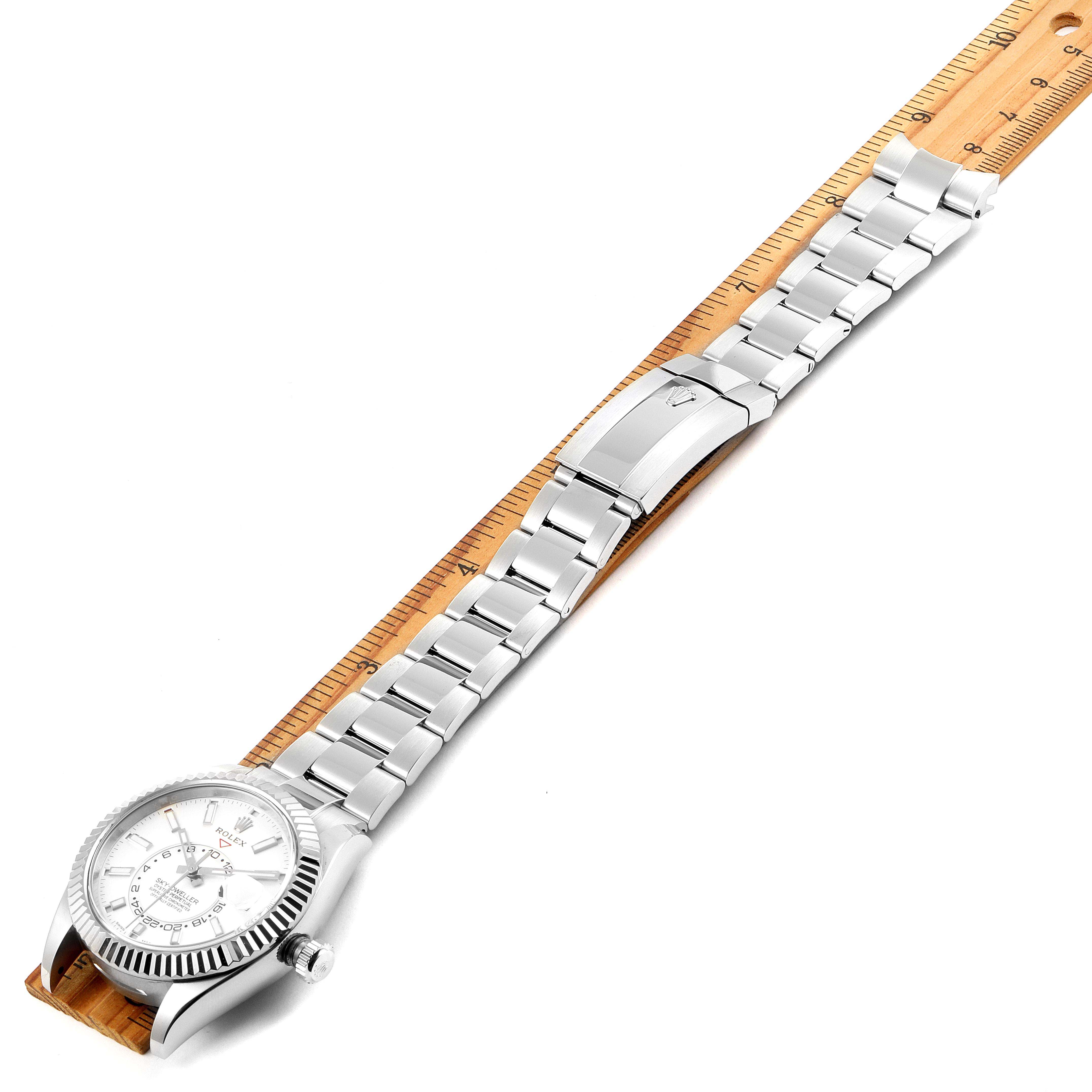 The image shows the Rolex Sky-Dweller 326934 Men's Stainless Steel White Dial 326934 Men's Stainless Steel White Dial watch lying flat, with the entire bracelet and the watch face visible, on top of a ruler.