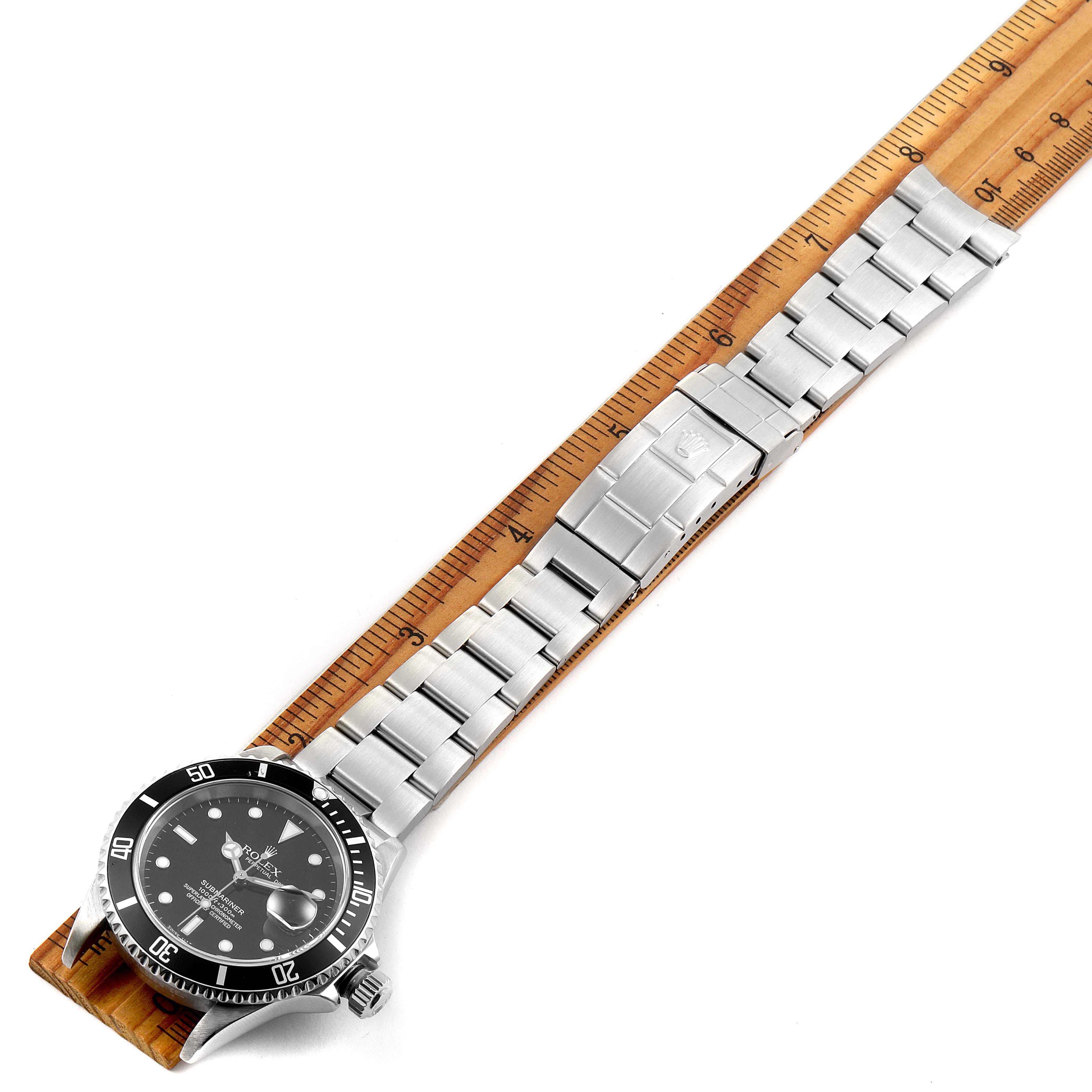This image shows a Rolex Submariner 16610 Men
s Stainless Steel Black Dial 16610 Men
s Stainless Steel Black Dial watch laid flat with its face, band, and clasp visible, measured against a ruler.