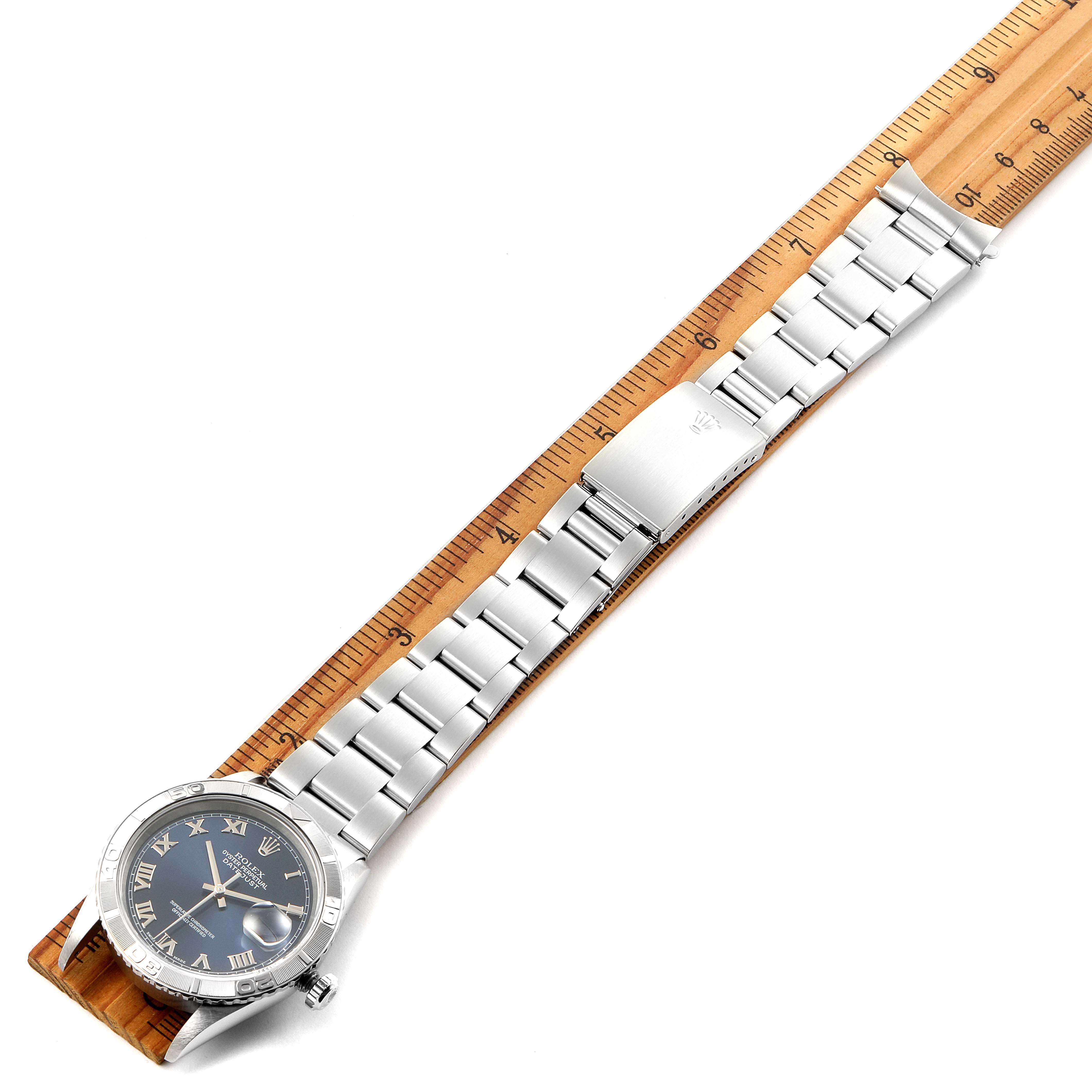 This image shows the Rolex Turn-o-Graph 16264 Men
s Stainless Steel Blue Dial 16264 Men
s Stainless Steel Blue Dial watch laid flat alongside a wooden ruler, highlighting the bracelet and face.