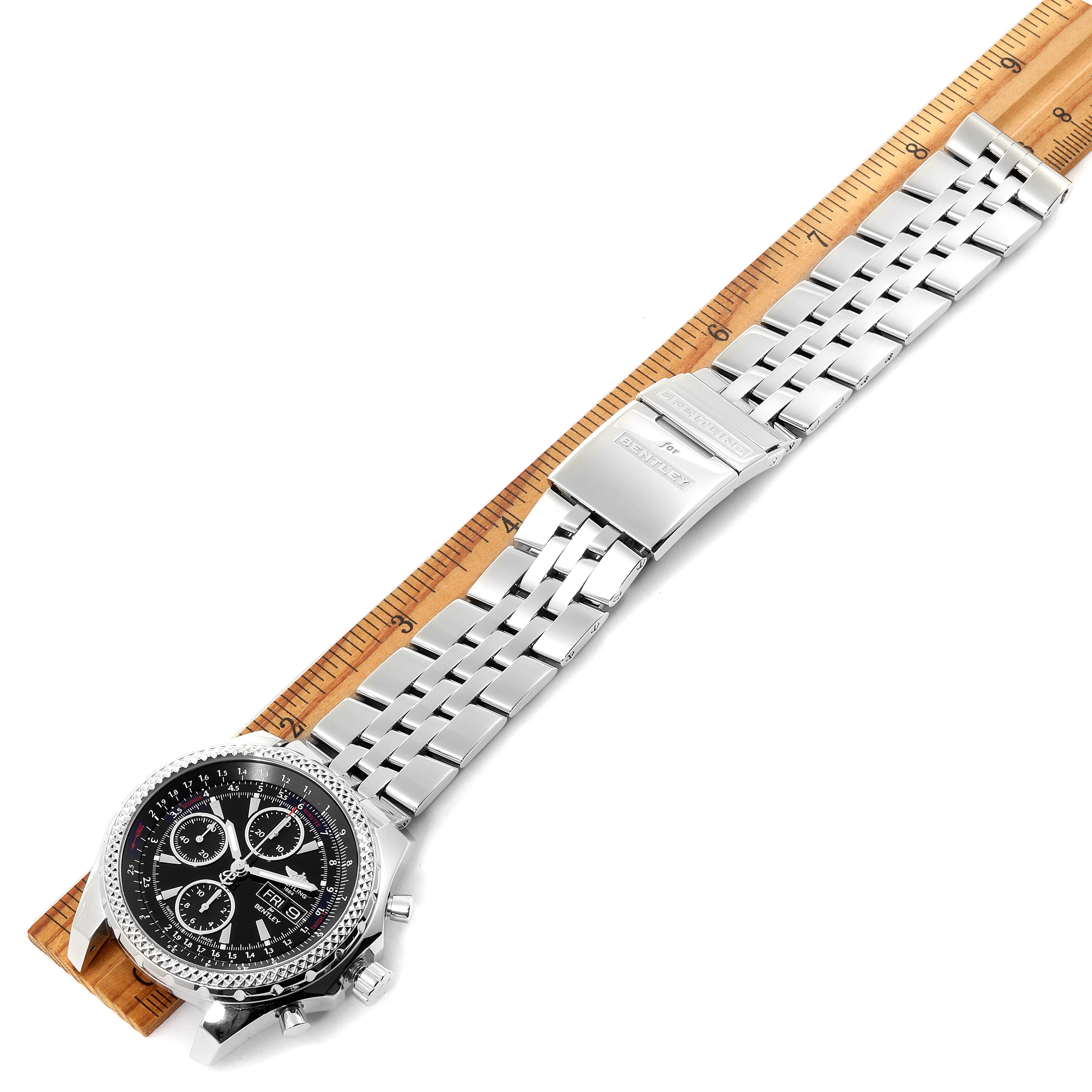 The Breitling Bentley A13362 Men's Stainless Steel Black Dial A13362 Men's Stainless Steel Black Dial watch is shown from a top-down angle, displaying the face, bezel, and metal bracelet on a ruler.