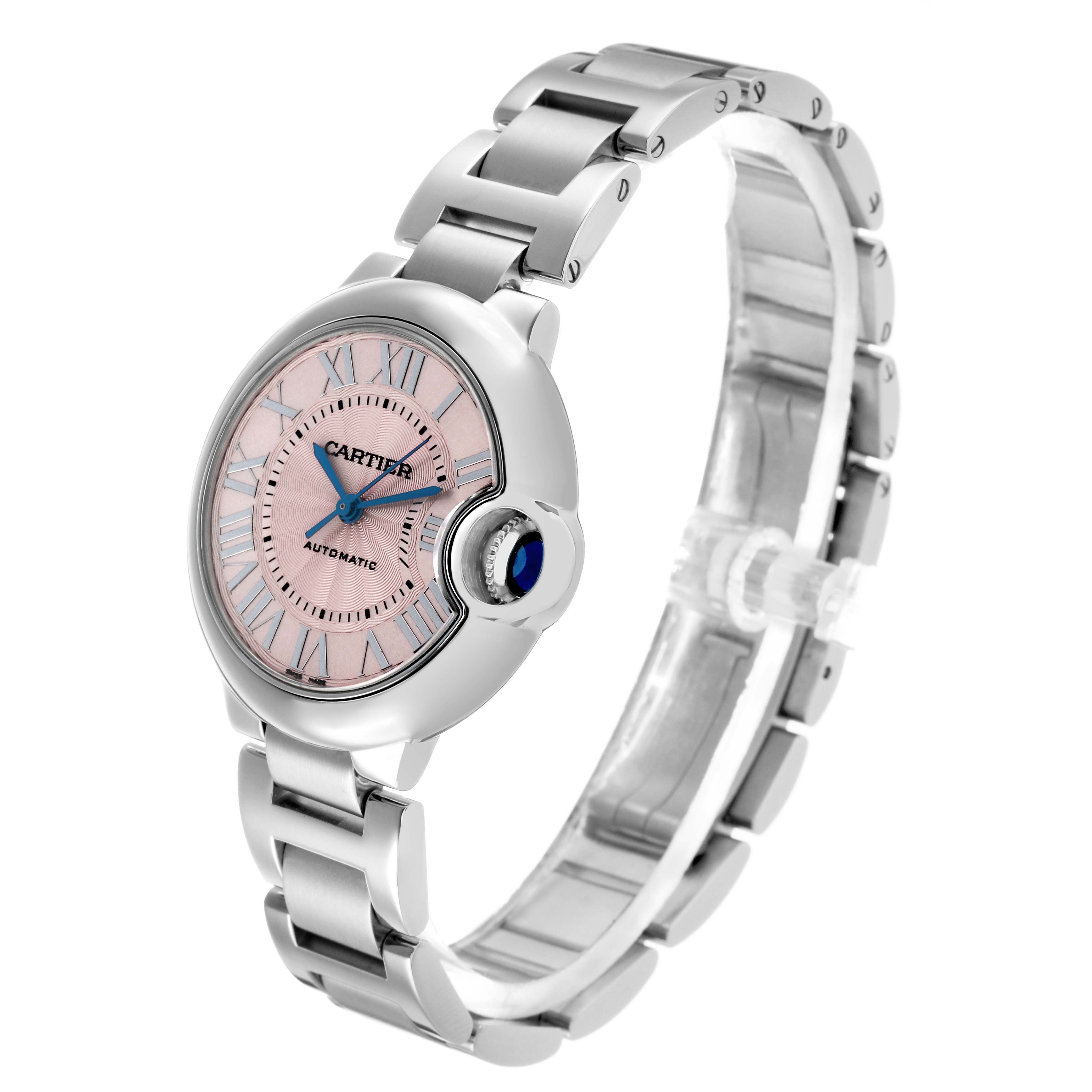 The Cartier Ballon Bleu W6920100 Women's Stainless Steel Pink Dial watch is shown at a three-quarter angle, highlighting its pink dial, blue hands, and metal bracelet.