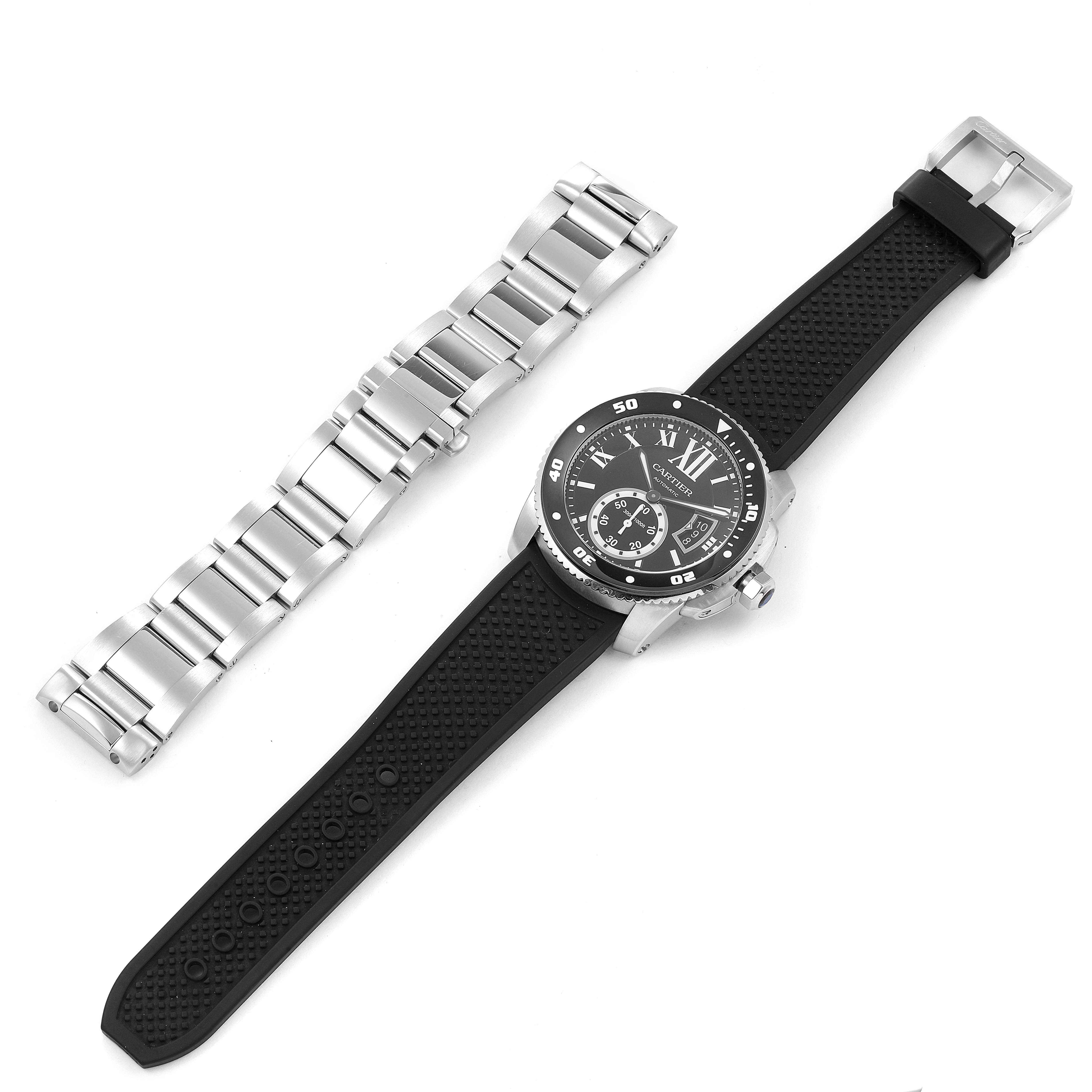 The image shows a Calibre de Cartier by Cartier with a black rubber strap and a separate stainless steel bracelet laid beside it.