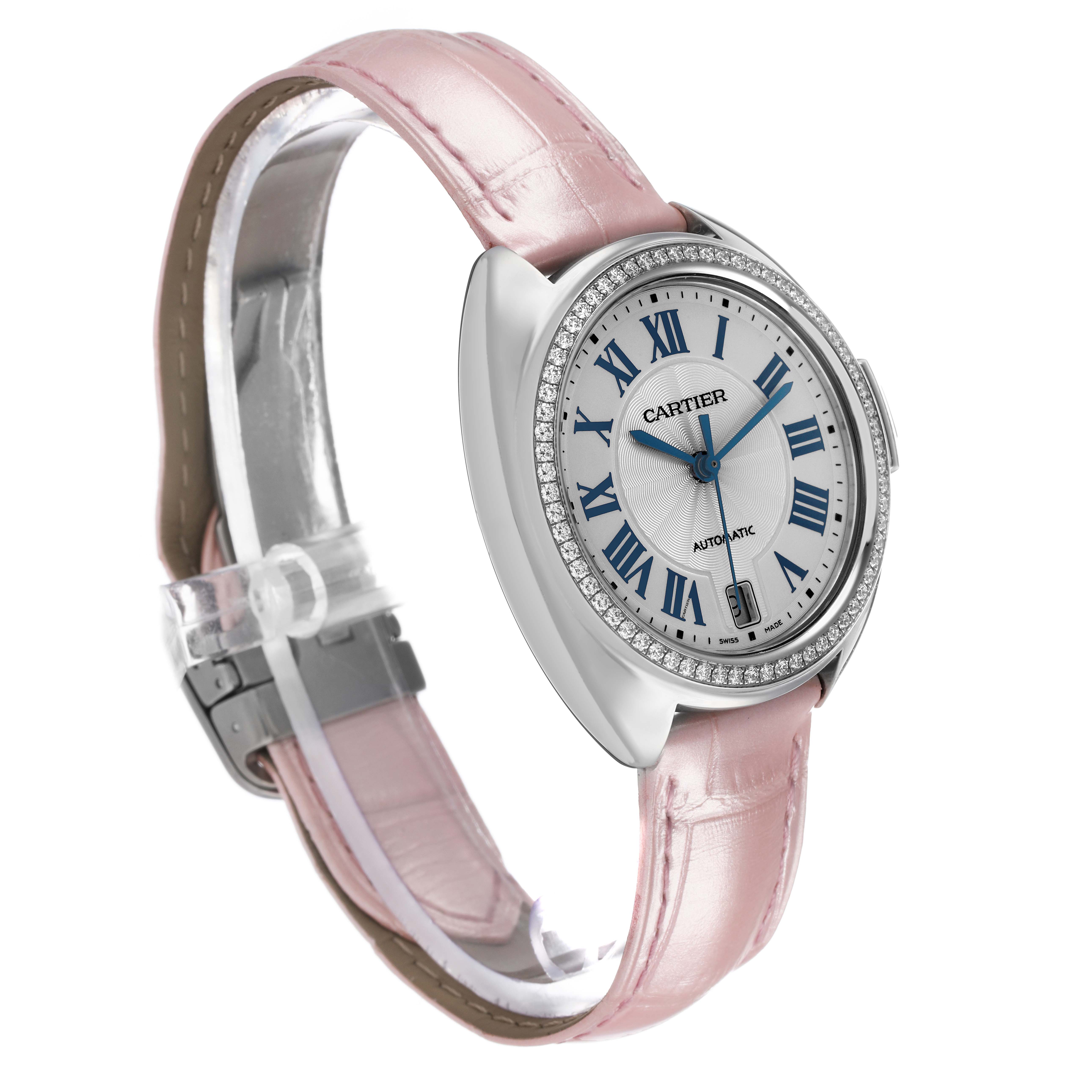 The Cartier Clé watch is shown at a three-quarter angle, highlighting the dial, pink leather strap, and diamond-set bezel.