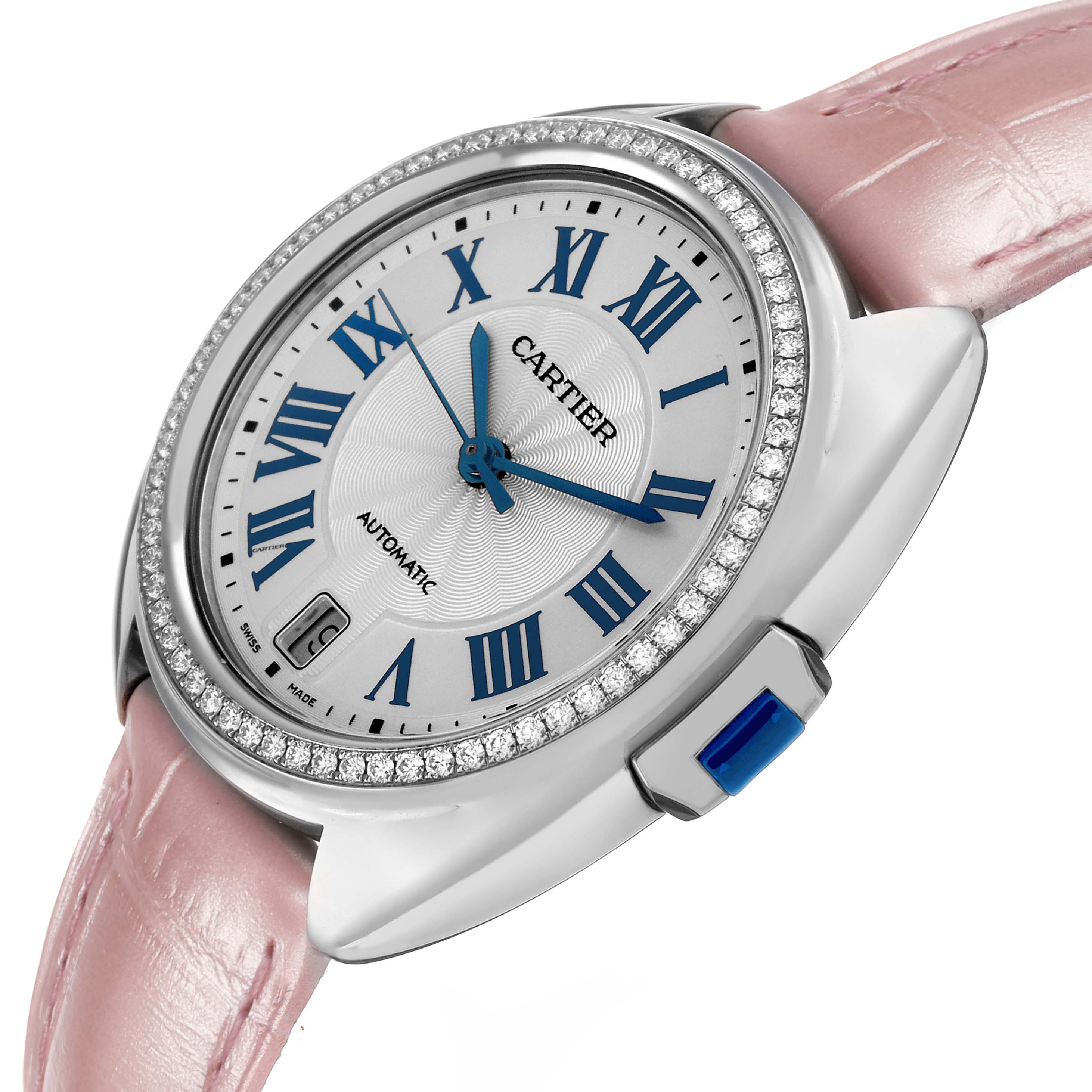 This Cartier Clé watch is shown from a side angle featuring its diamond-encrusted bezel, blue hands, pink strap, and crown.