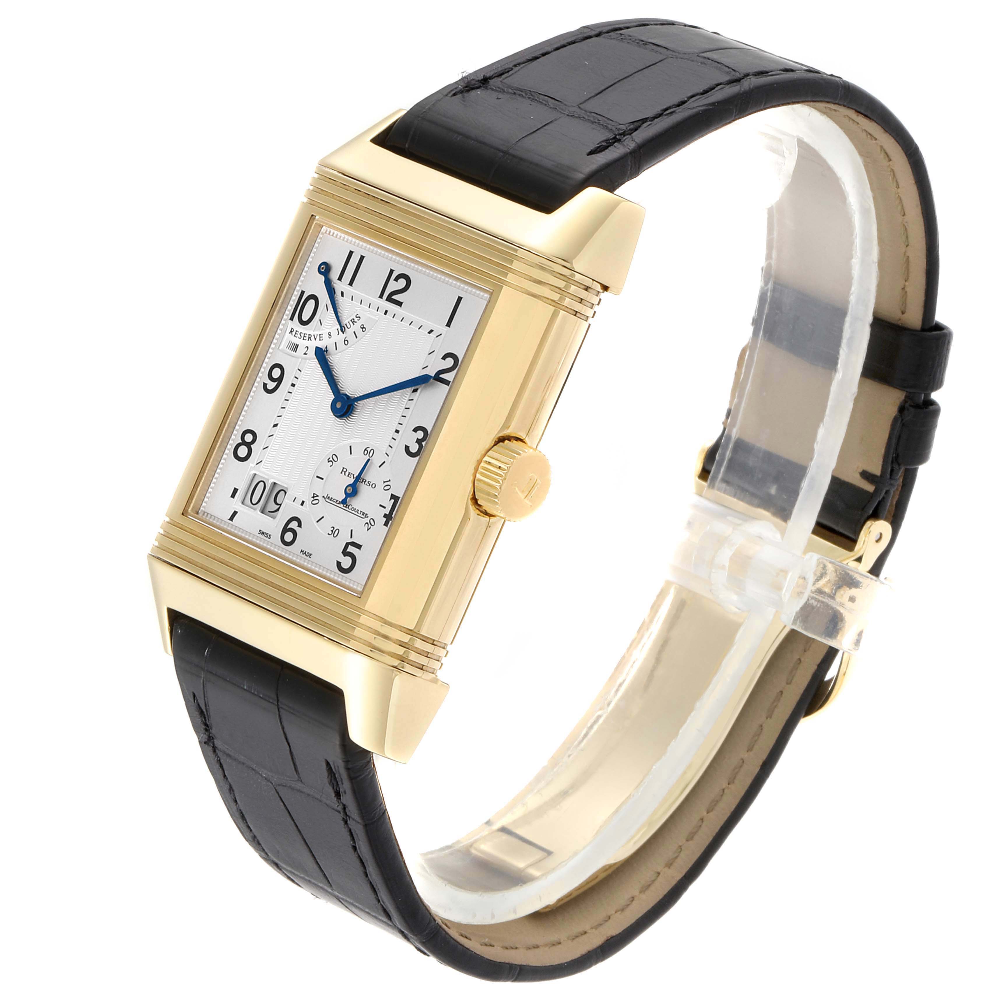 The Jaeger-LeCoultre Reverso watch is shown at a three-quarter angle, highlighting its rectangular face, gold case, and black leather strap.