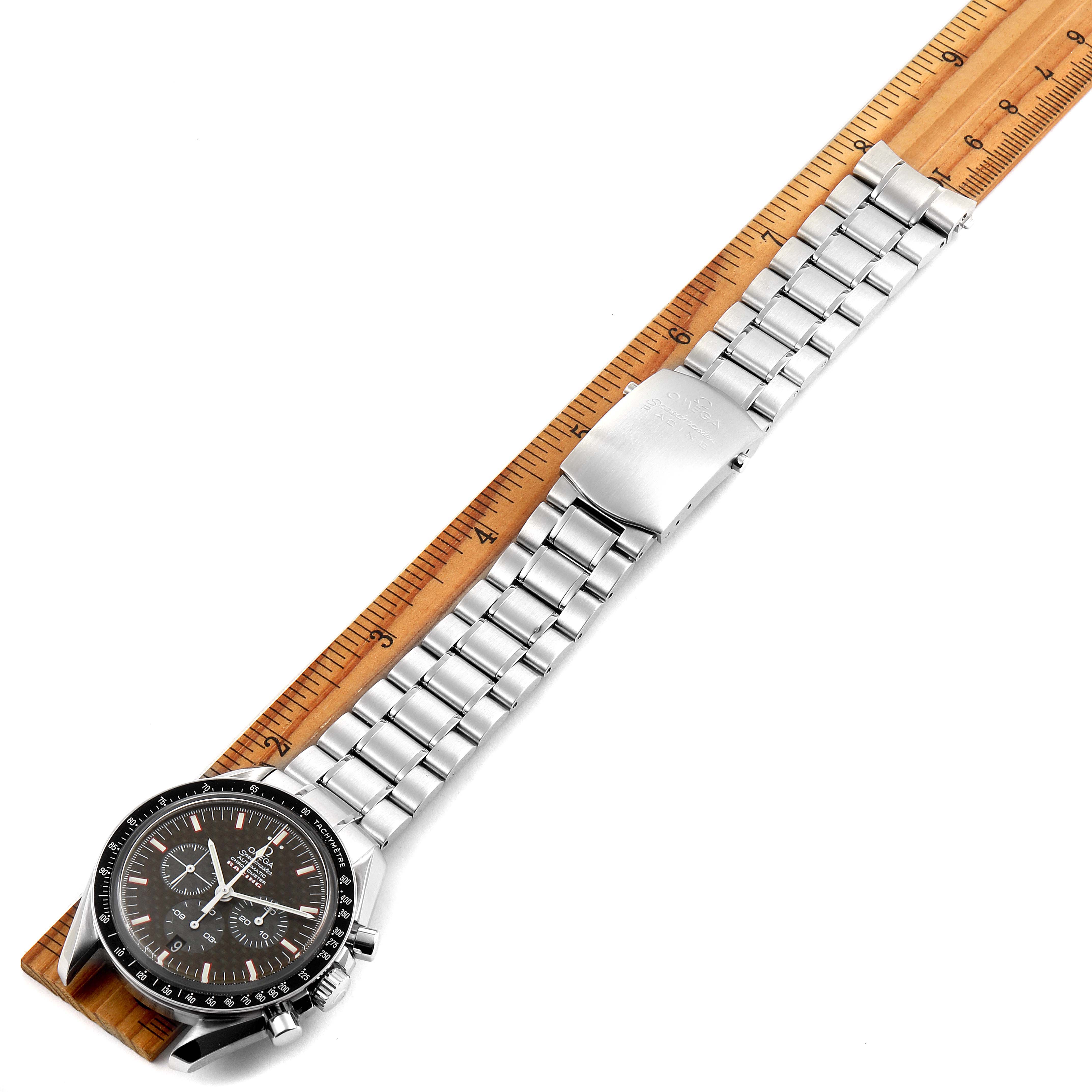 The image shows an Omega Speedmaster 3552.59.00 Men
s Stainless Steel Black Dial 3552.59.00 Men
s Stainless Steel Black Dial watch laid flat on a ruler, highlighting the bracelet and face from a top-down angle.