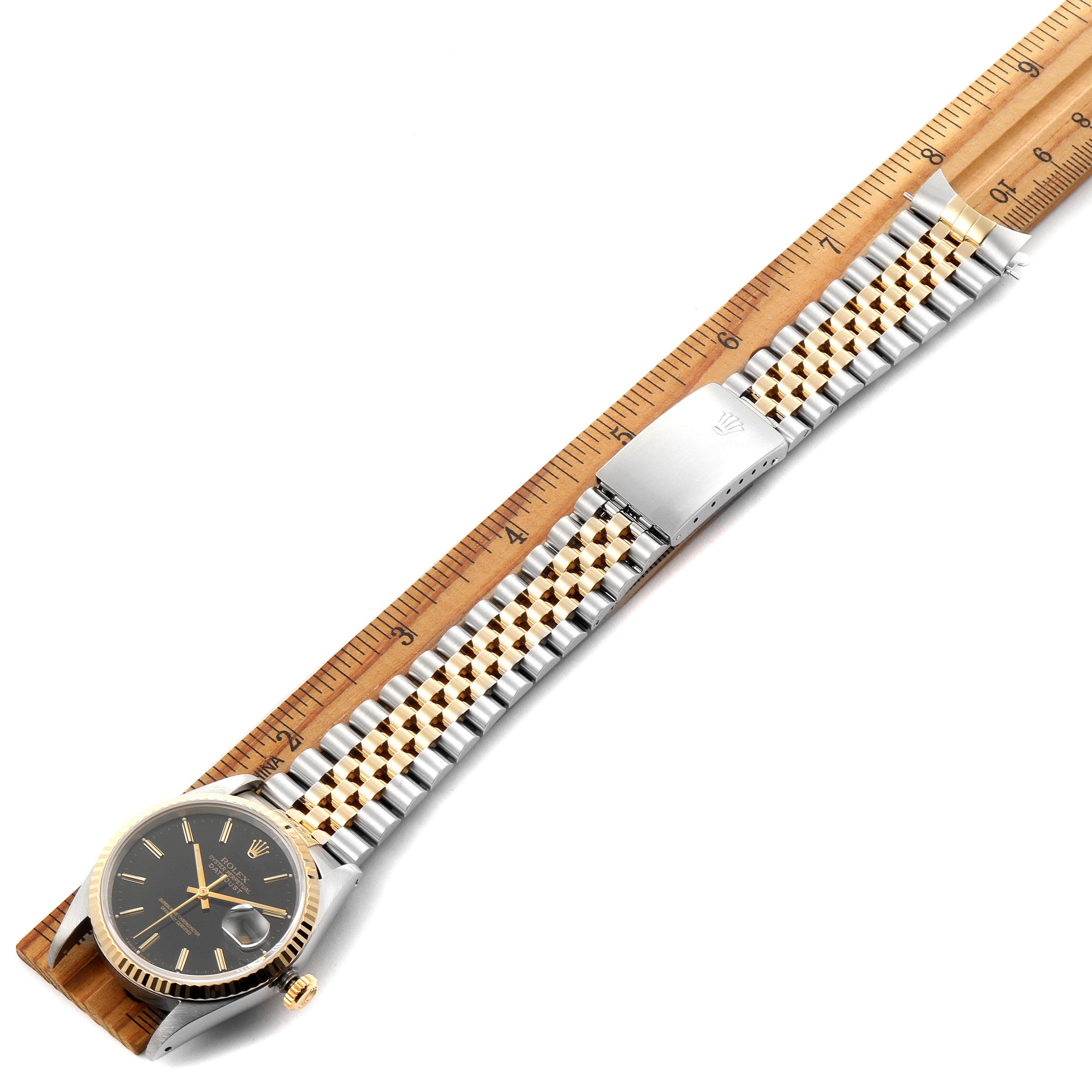 The image shows a Rolex Datejust 16233 Men's Steel and Gold (two tone) Black Dial 16233 Men's Steel and Gold (two tone) Black Dial watch laid flat with its bracelet extended beside a ruler for scale.