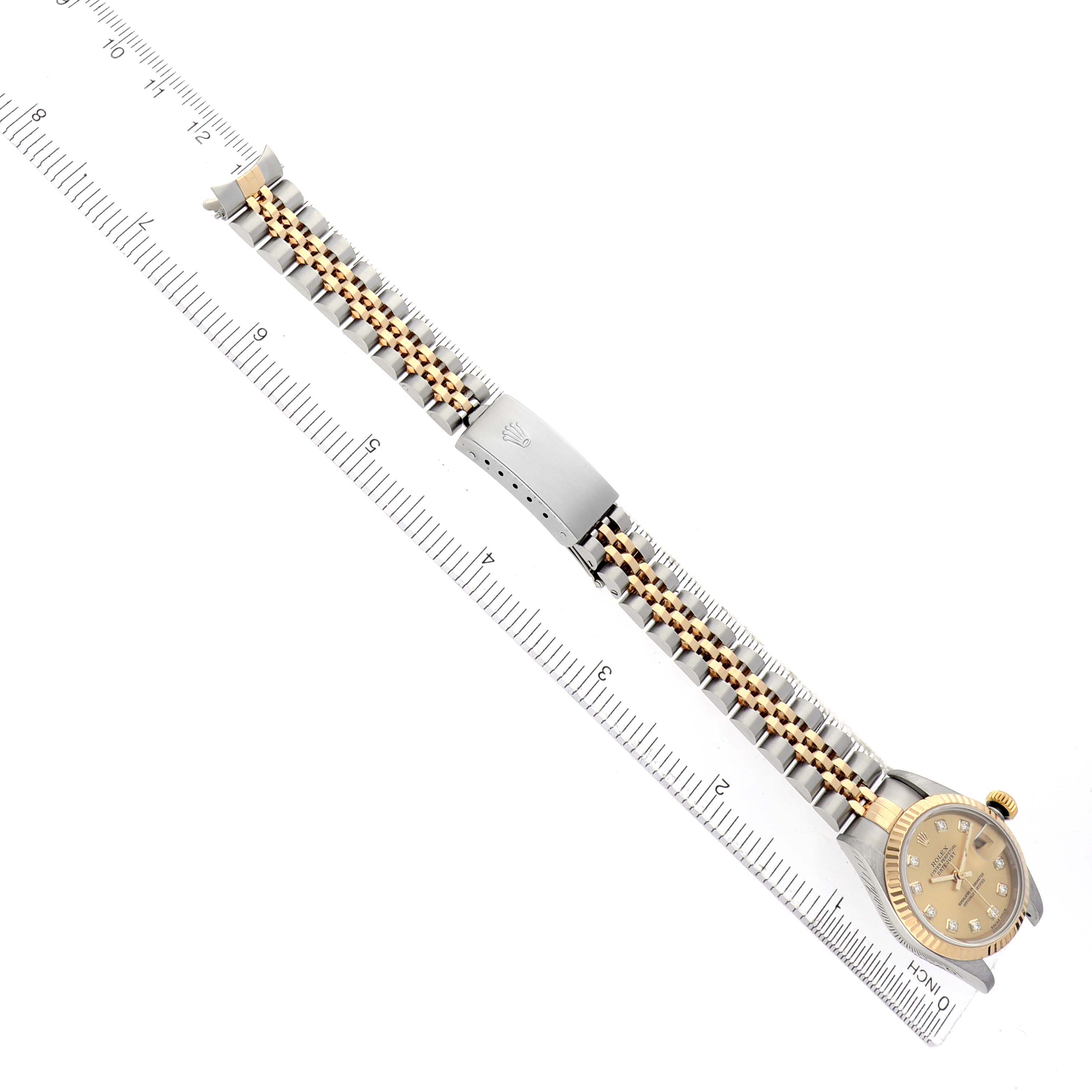 The Rolex Datejust 79173 Women's Steel and Gold (two tone) Champagne Dial watch is shown from above, displaying the face, bezel, bracelet, and clasp beside a ruler for scale.