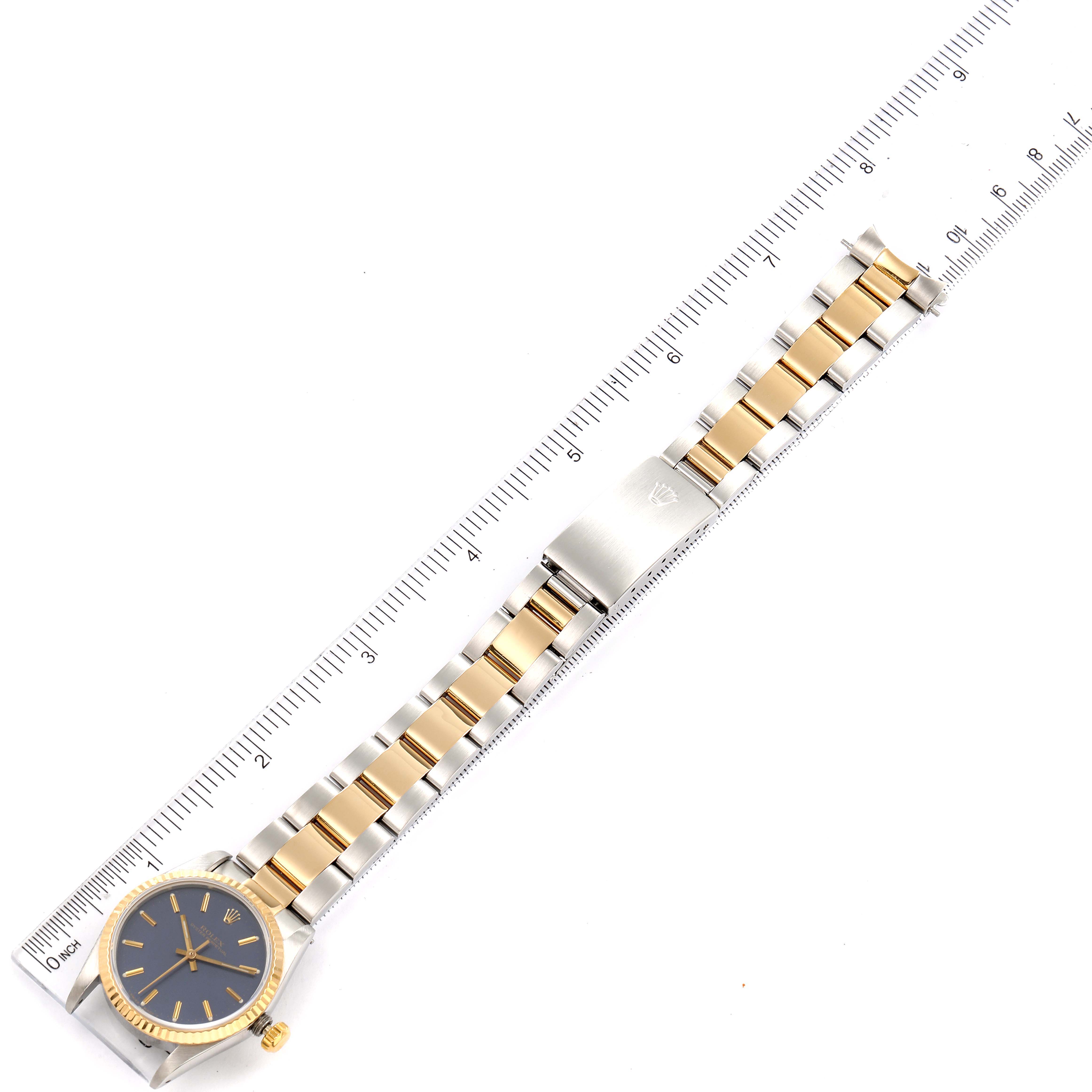 This image shows a top-down view of a Mid-Size Rolex watch, displaying the face, bracelet, and clasp next to a ruler for scale.