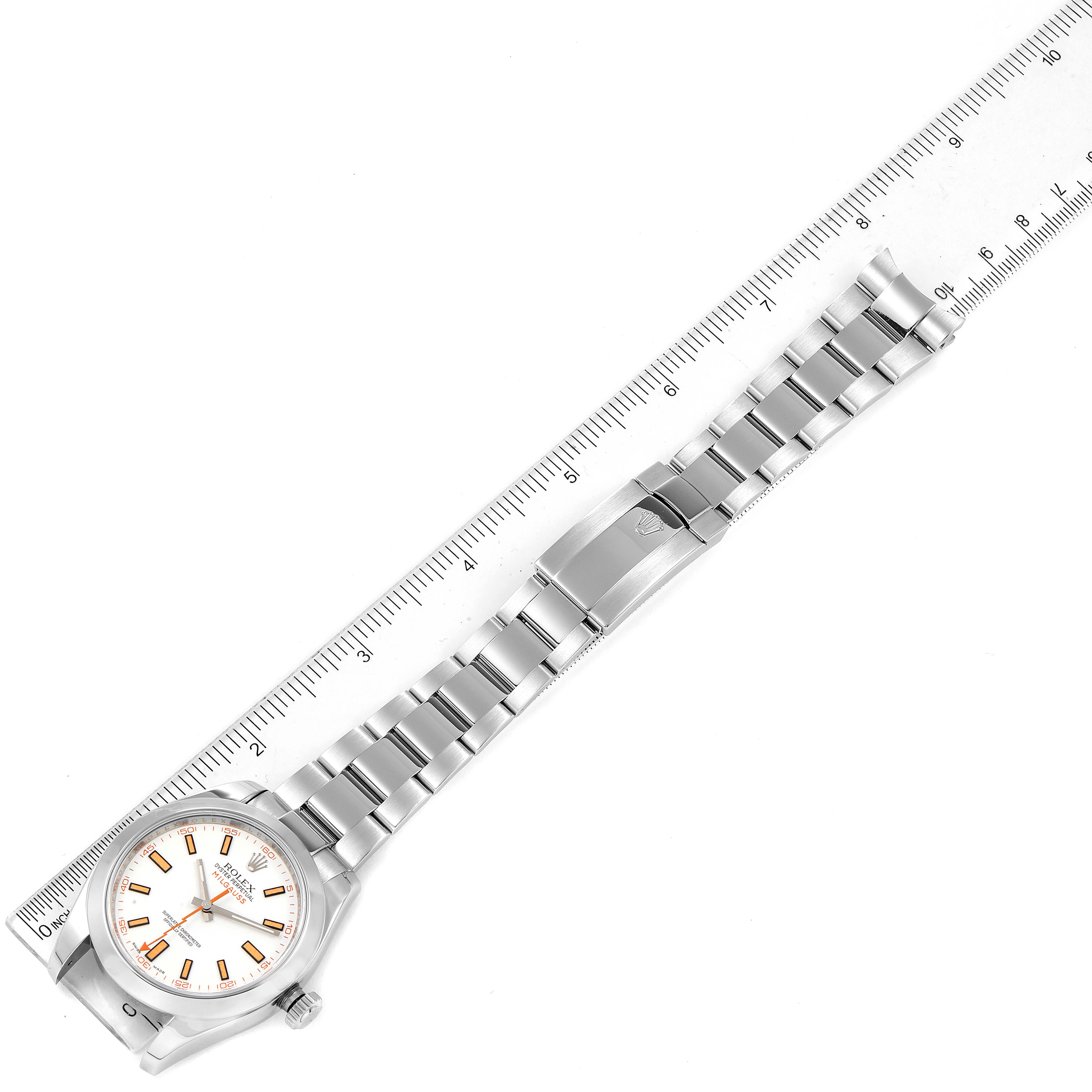 The Rolex Milgauss 116400V Men
s Stainless Steel White Dial 116400V Men
s Stainless Steel White Dial watch is shown from a top-down angle alongside a ruler, displaying its full bracelet and face.