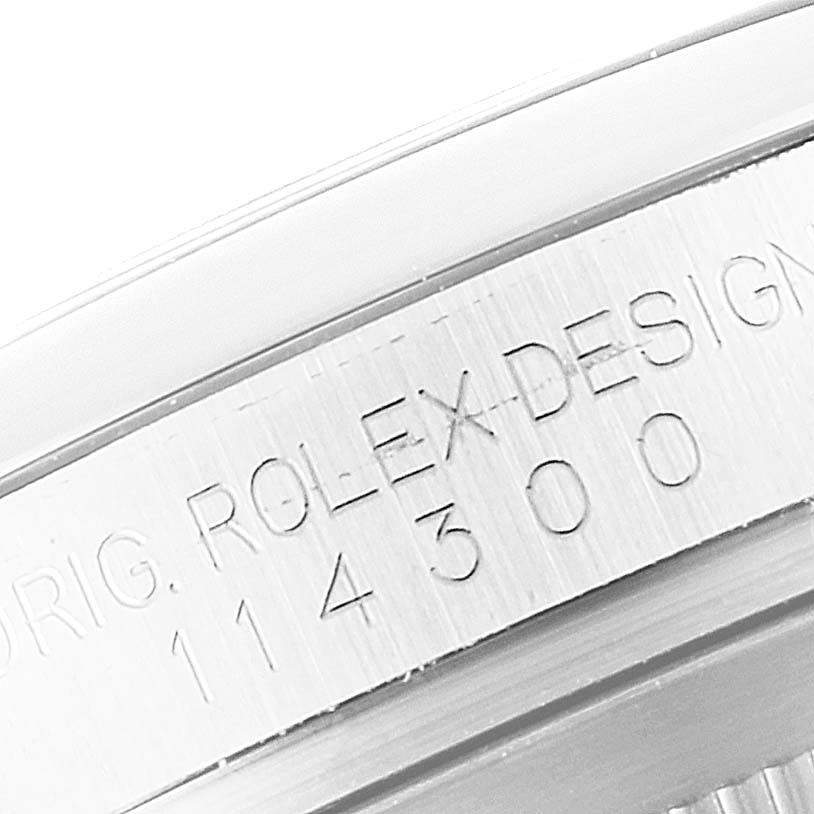 The image shows a close-up angle of the bezel engraving on a Rolex Oyster Perpetual 114300 Men
s Stainless Steel Black Dial 114300 Men
s Stainless Steel Black Dial watch, displaying the model number.