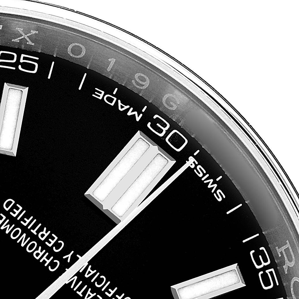 The image shows a close-up of the dial and partial bezel of a Rolex Oyster Perpetual 116000 Men's Stainless Steel Black Dial, highlighting the minute markers.