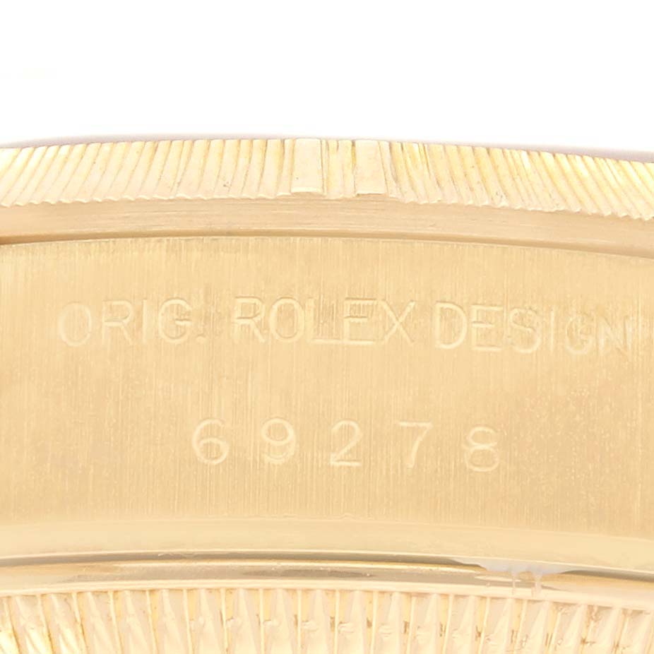The image shows a close-up of the Rolex President 69278 Women's Yellow Gold Champagne Dial 69278 Women's Yellow Gold Champagne Dial model case with engraved details and part of the bezel.