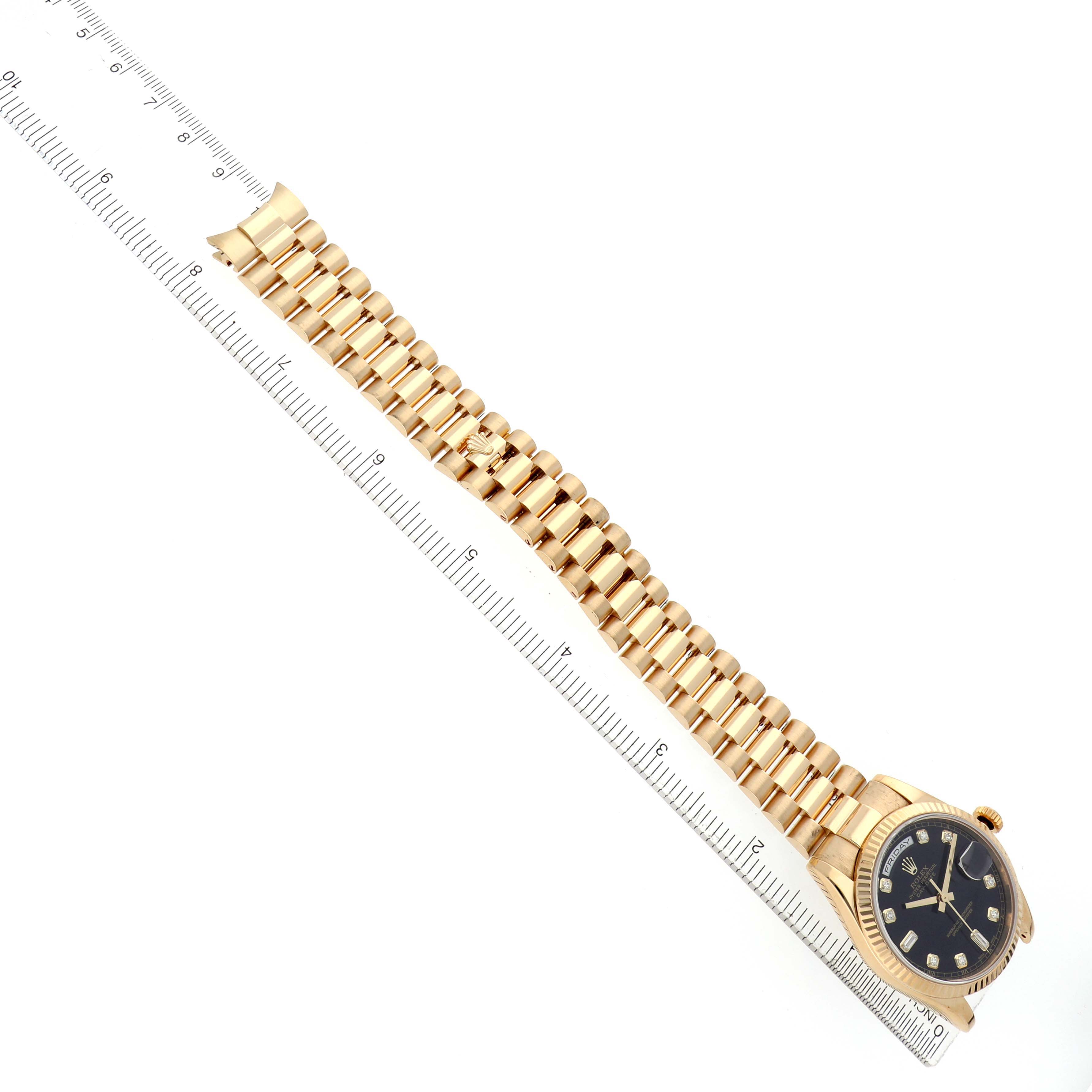 The image shows a Rolex President 118238 Men's Yellow Gold Black Dial watch at a top-down angle, highlighting the bracelet and face alongside a ruler.