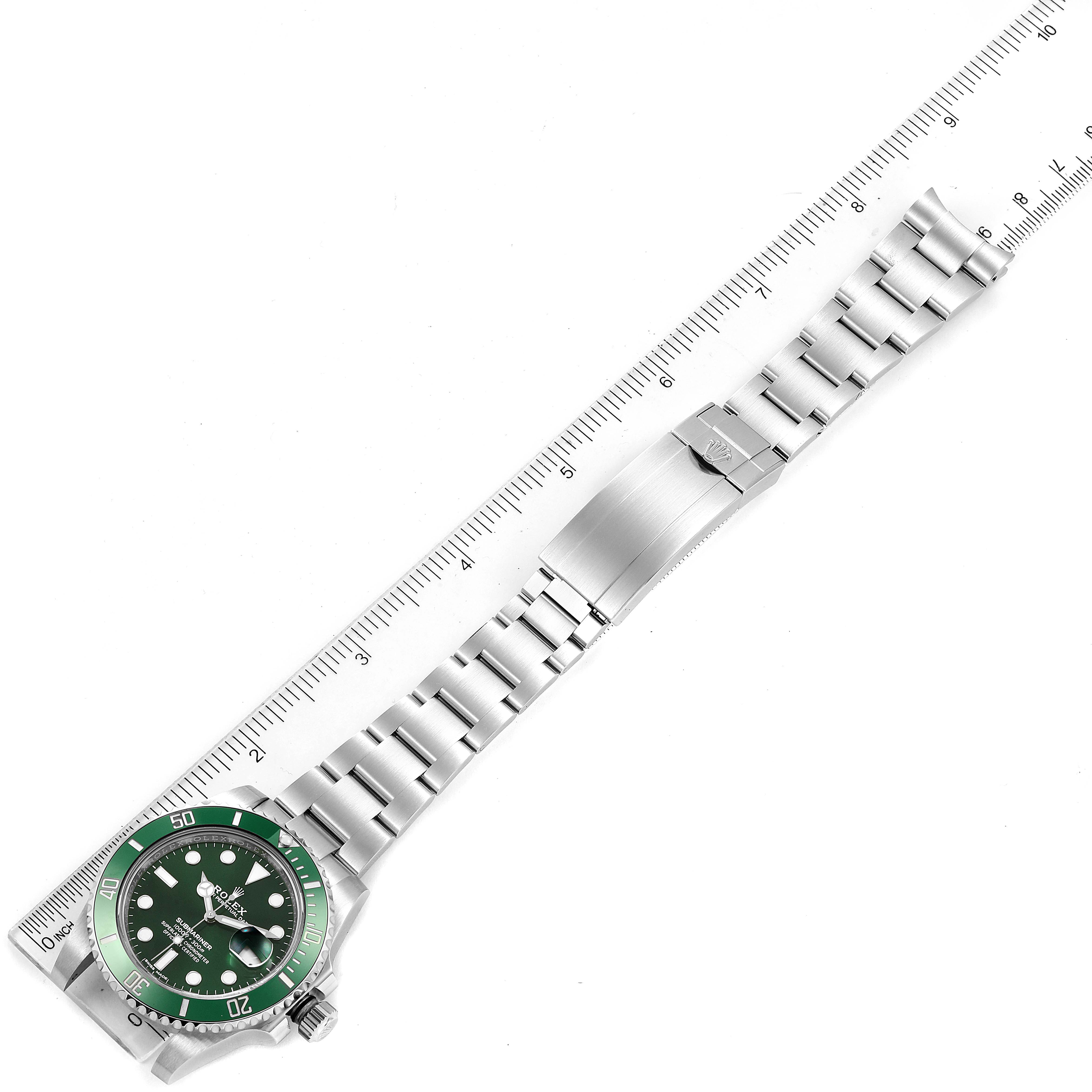The image shows a top-down view of a Rolex Submariner 116610LV Men
s Stainless Steel Green Dial 116610LV Men
s Stainless Steel Green Dial watch with a green bezel, silver bracelet, and a ruler for scale.