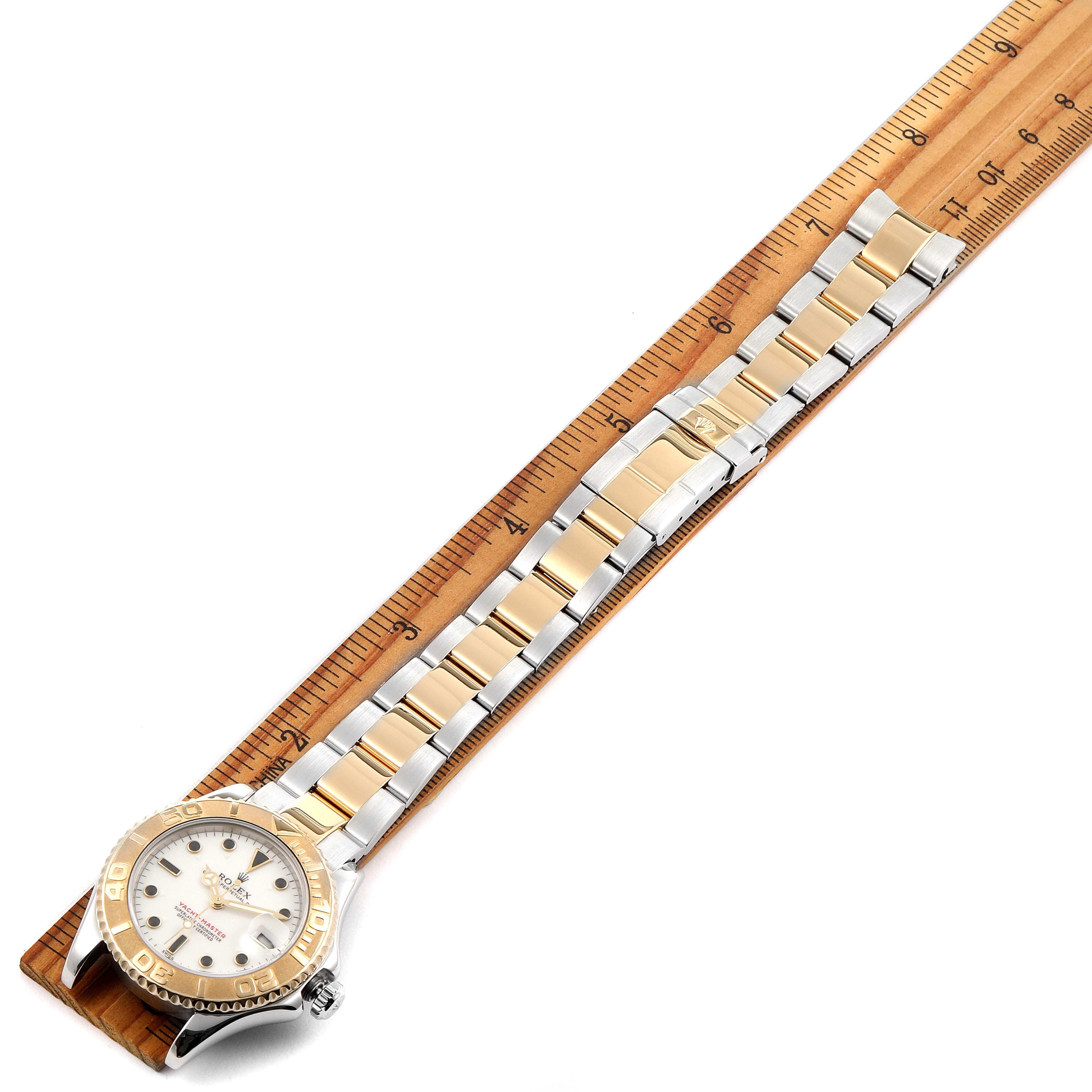 The Rolex Yacht-Master 168623 Men's Steel and Gold (two tone) White Dial 168623 Men's Steel and Gold (two tone) White Dial watch is shown from an overhead angle, highlighting its face and metal band, measured against a ruler.