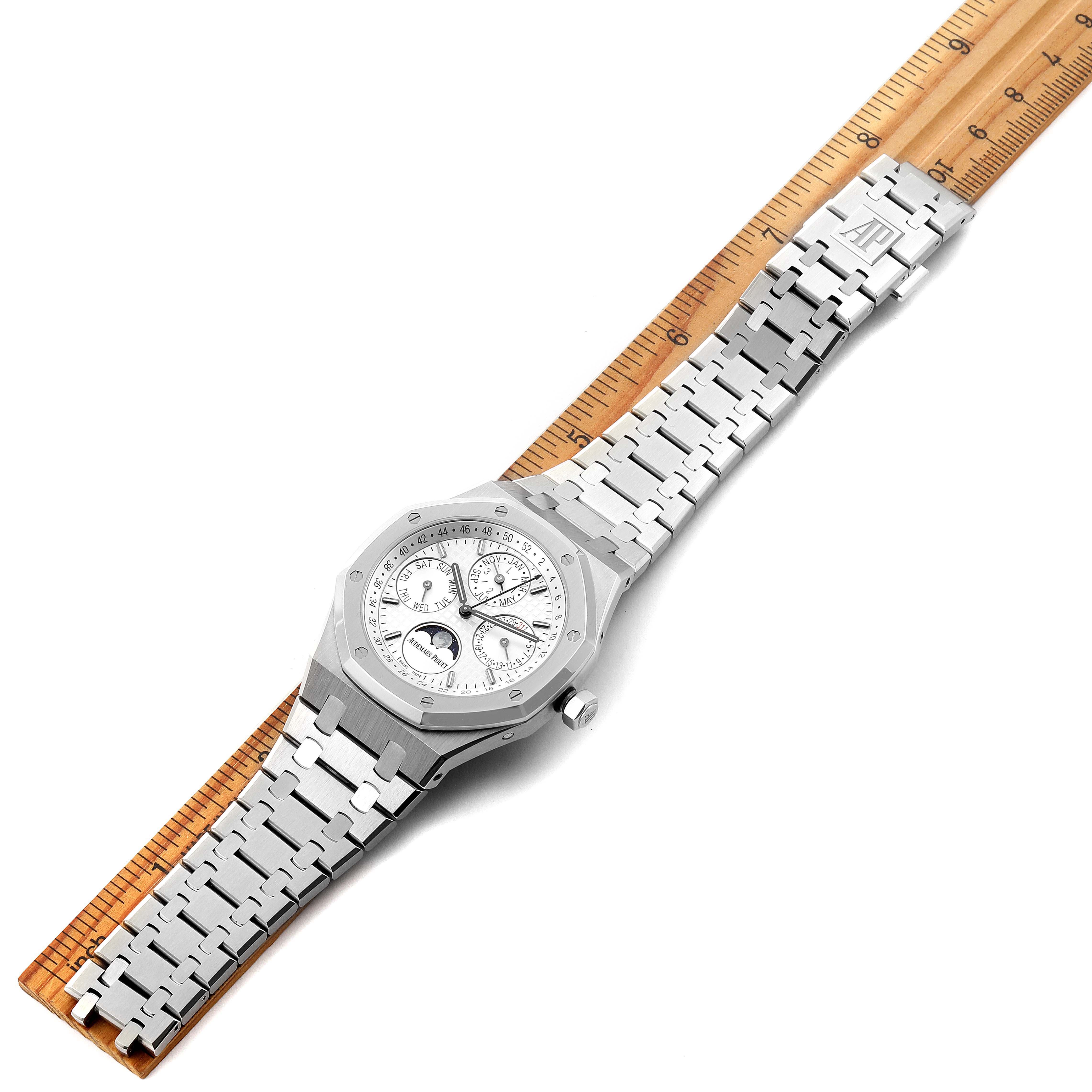 The image shows the face and full bracelet of an Audemars Piguet Royal Oak 26574ST.OO.1220ST.01 Men's Stainless Steel Silver Dial 26574ST.OO.1220ST.01 Men's Stainless Steel Silver Dial watch, lying flat and aligned with a wooden ruler.