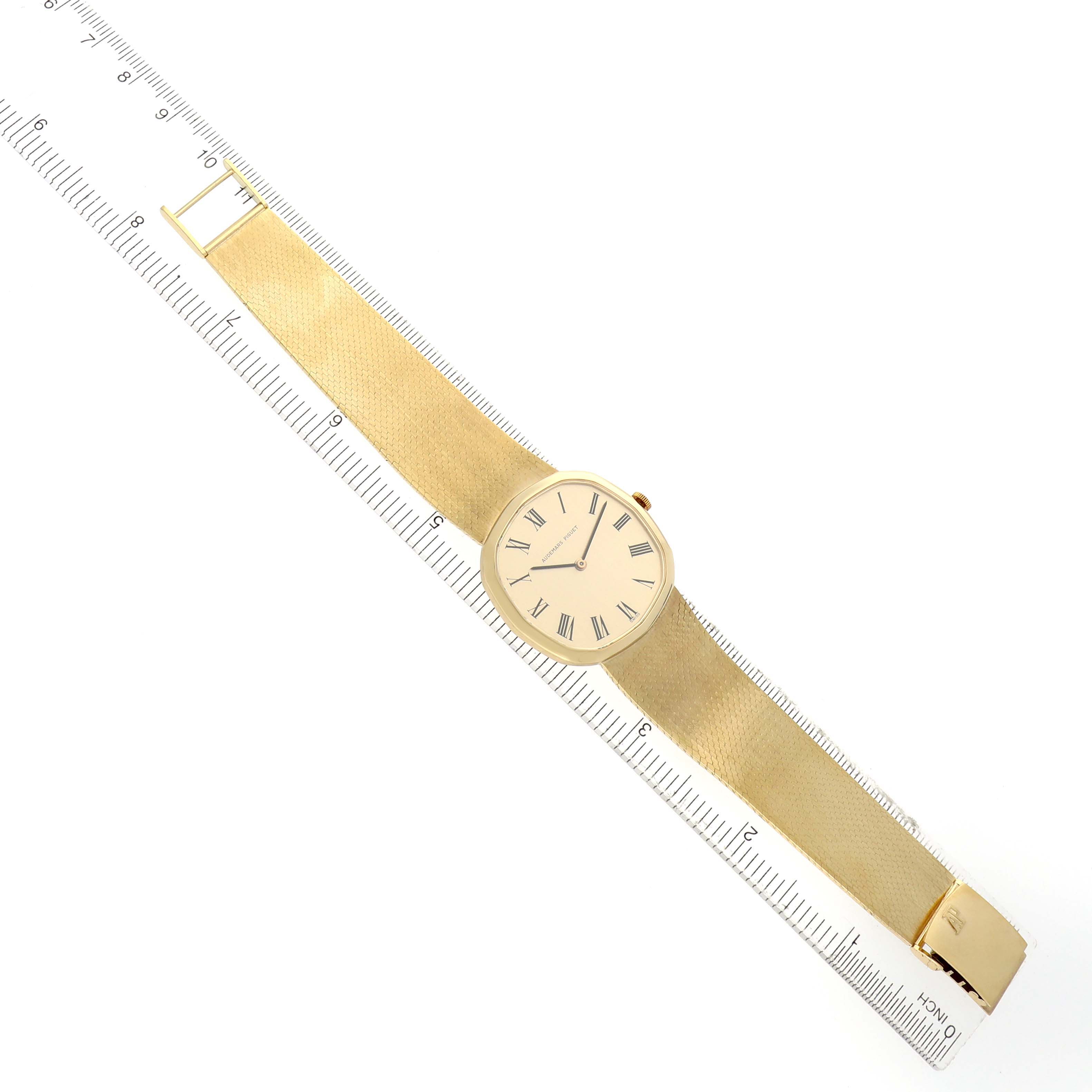 The Audemars Piguet Vintage Men's Yellow Gold Champagne Dial watch is shown from a top view, displaying the full face with Roman numerals and a gold bracelet.