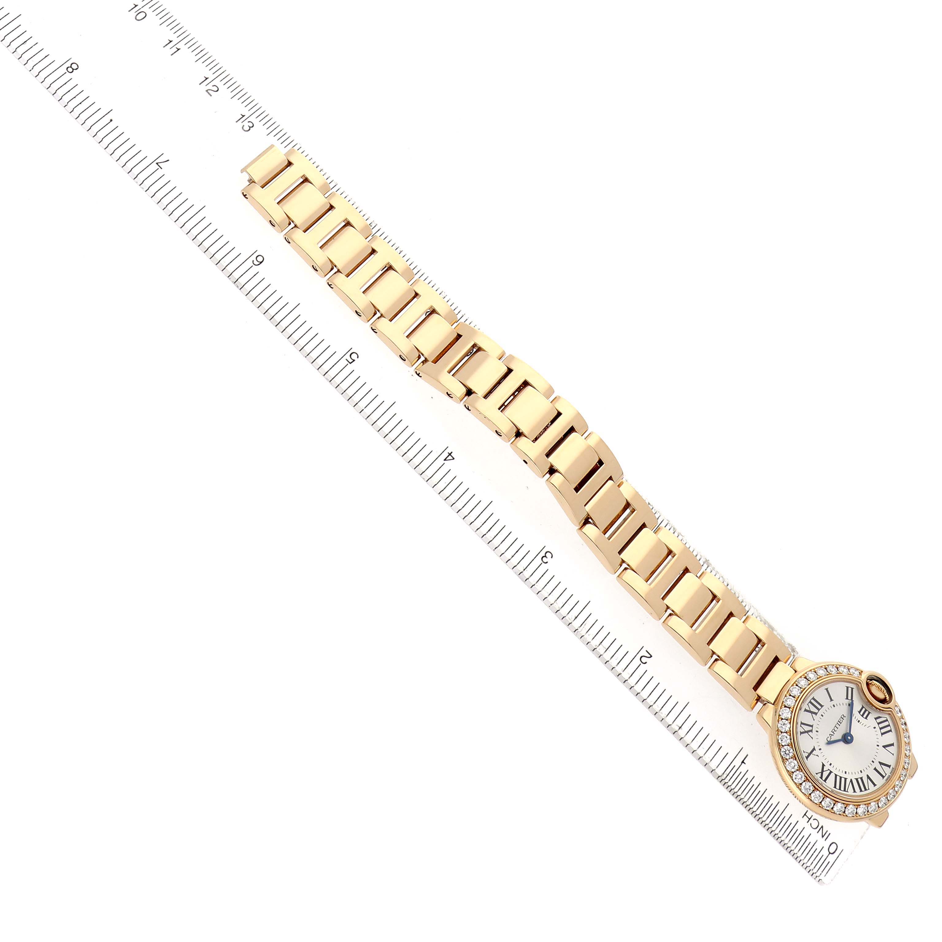 The Cartier Ballon Bleu WE9001Z3 Women's Yellow Gold Silver Dial watch is displayed flat with the entire bracelet and face visible, next to a ruler for scale.