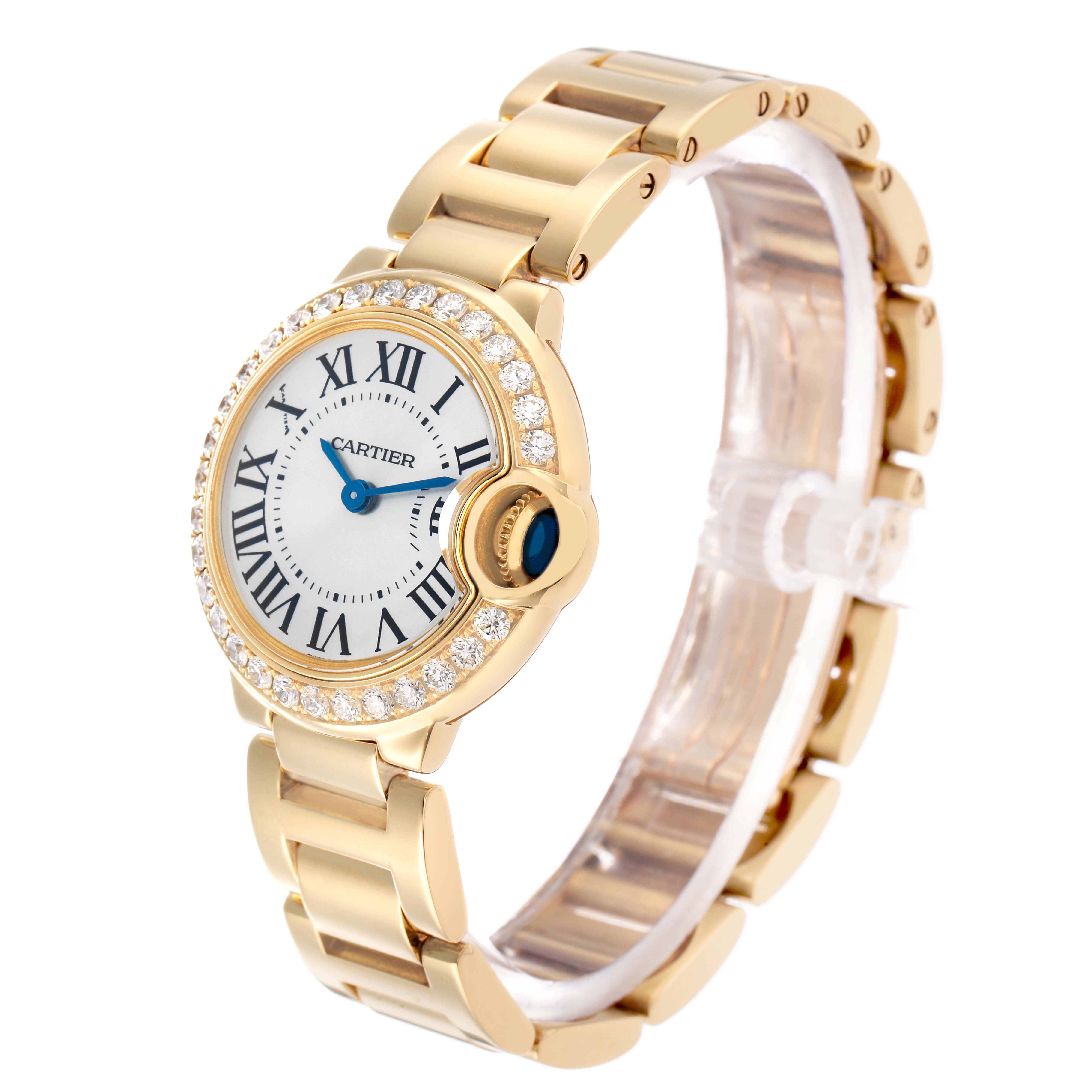 The Cartier Ballon Bleu WE9001Z3 Women's Yellow Gold Silver Dial watch is shown at a three-quarter angle, highlighting its bracelet, diamond bezel, and Roman numeral dial.